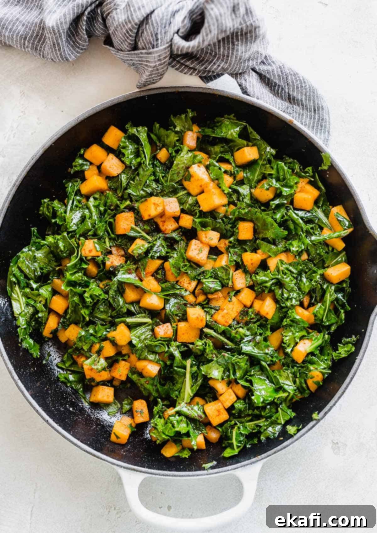 Roasted Butternut Squash and Kale 7 Overhead photo of vibrant Butternut Squash and Kale in a skillet on a white background, ready to be served.