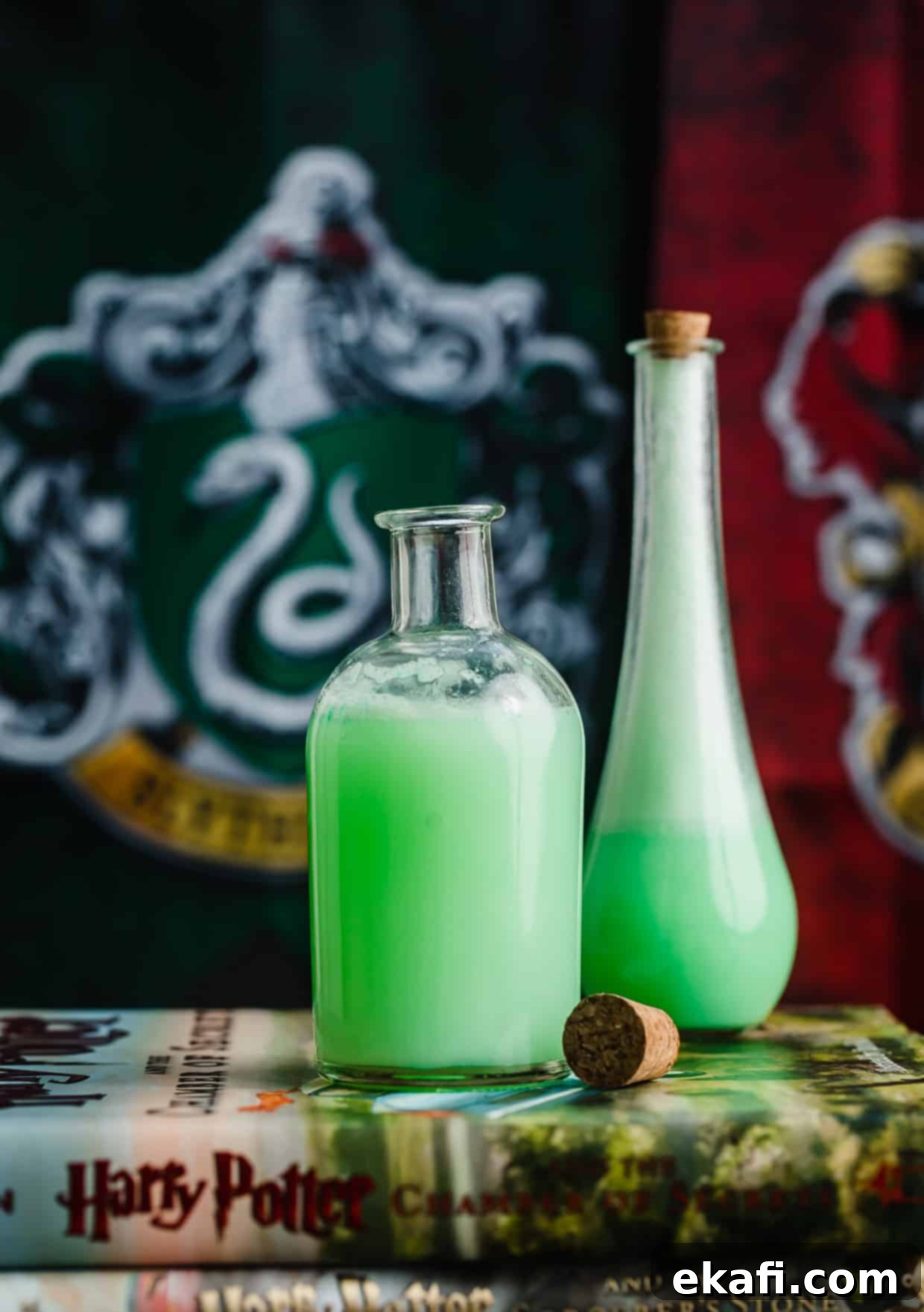 Shape-Shifter's Brew 6 Two magical potion jars brimming with green Polyjuice Potion, resting on an open copy of the Harry Potter Chamber of Secrets book, creating a perfectly themed display.