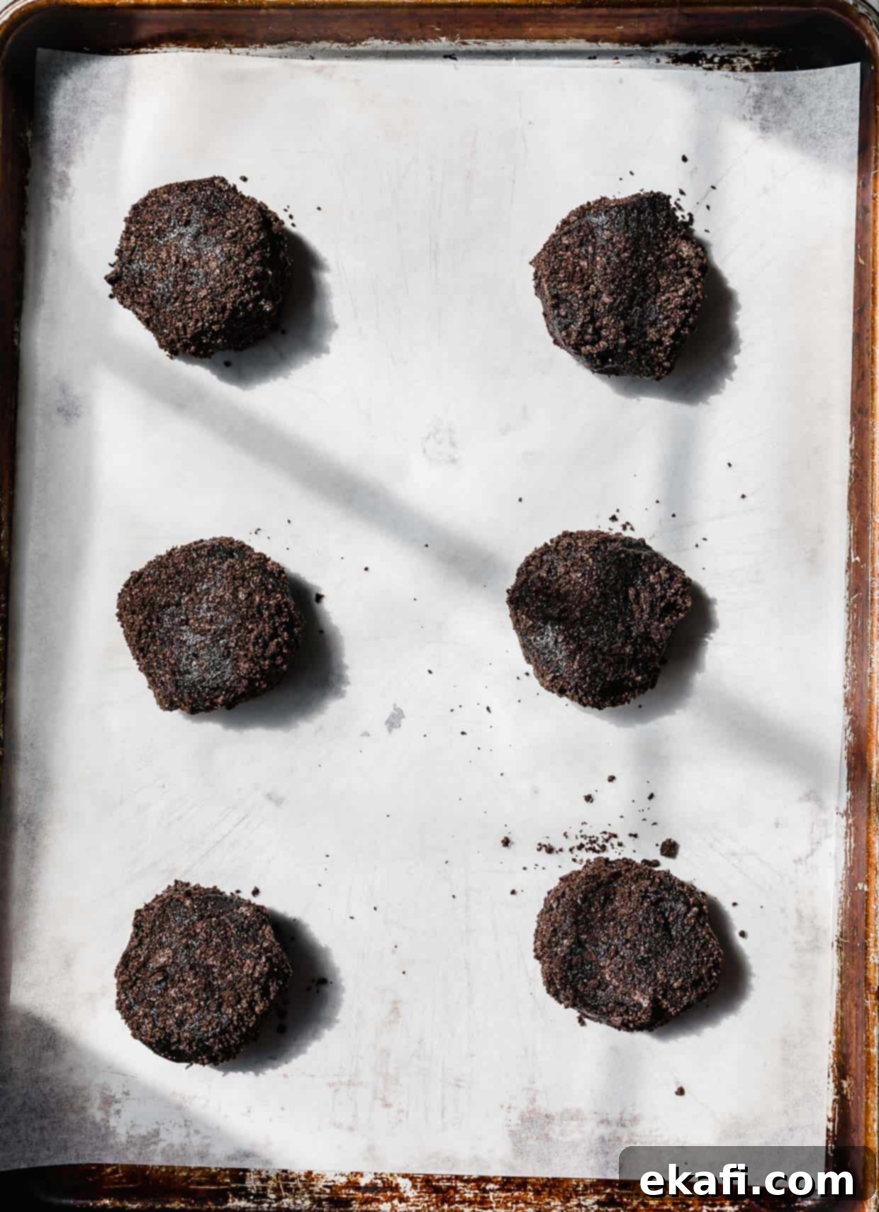 Oreo Mud Pie Cookies 7 Six black Dirt Cake Cookie dough balls on a white parchment lined baking sheet.