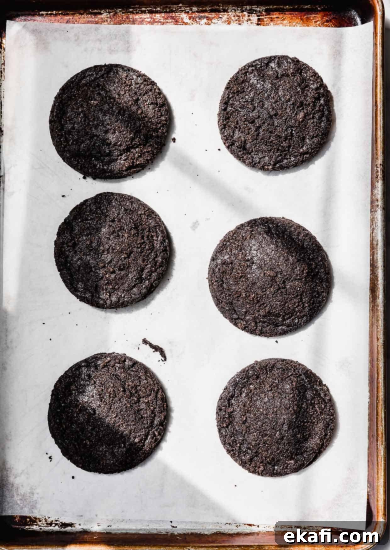 Oreo Mud Pie Cookies 8 Six baked Dirt Cake Cookies on a parchment lined baking sheet.