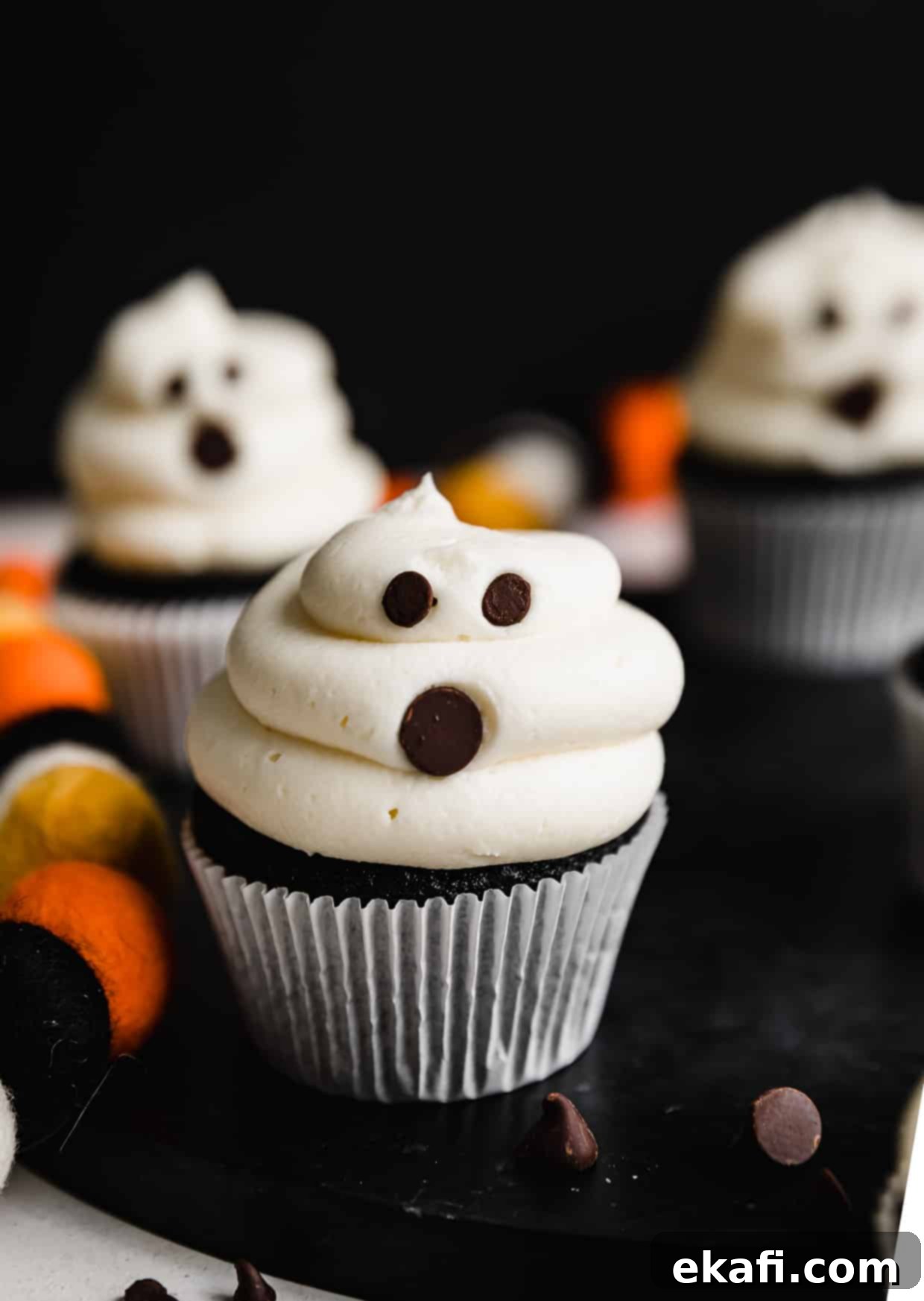 Phantom Frosted Treats 7 White frosting covered cupcakes with chocolate chips stuck into the frosting to make Ghost Cupcakes.