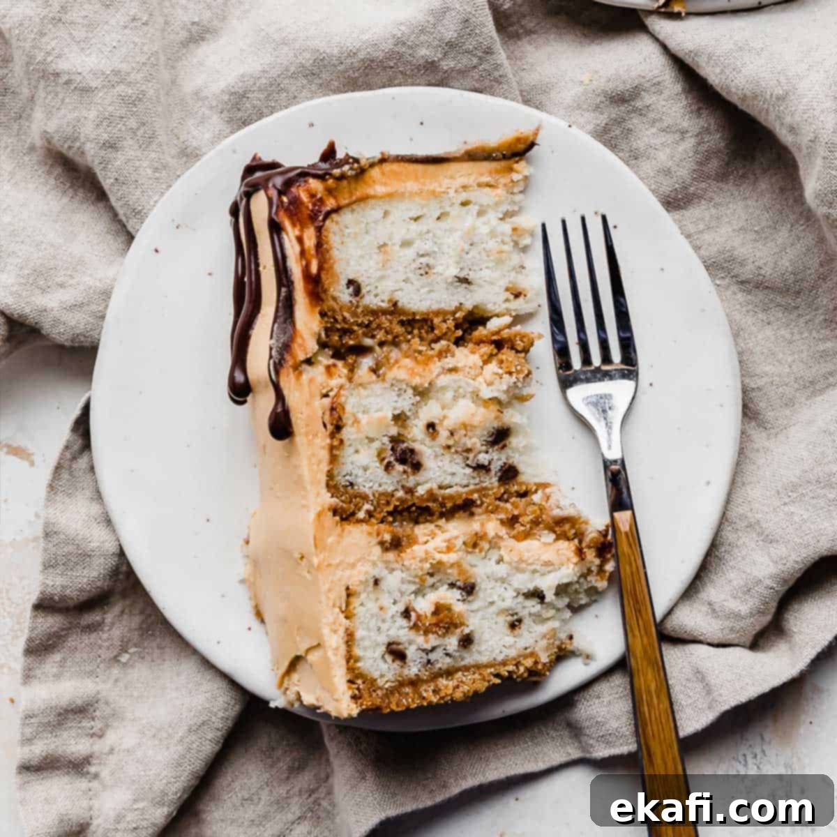 Petite Cake Perfection 9 A slice of 7 Layer Bar Cake on a white plate, showing the distinct layers of graham cracker crust, cake, filling, and frosting.