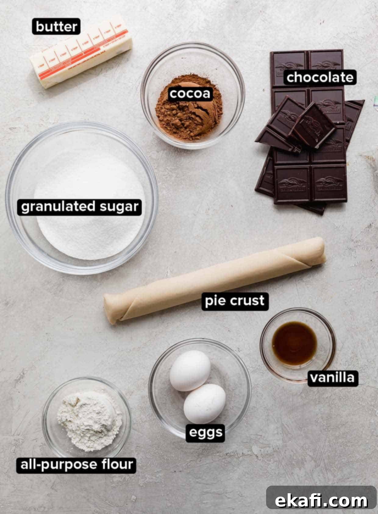 Καρυδόπιτα Μπράουνι 3 Συστατικά Brownie Pie σε ανοιχτό γκρι φόντο, συμπεριλαμβανομένων σοκολάτας, κακάο, κρούστας πίτας, αυγών, βανίλιας, βουτύρου και ζάχαρης.