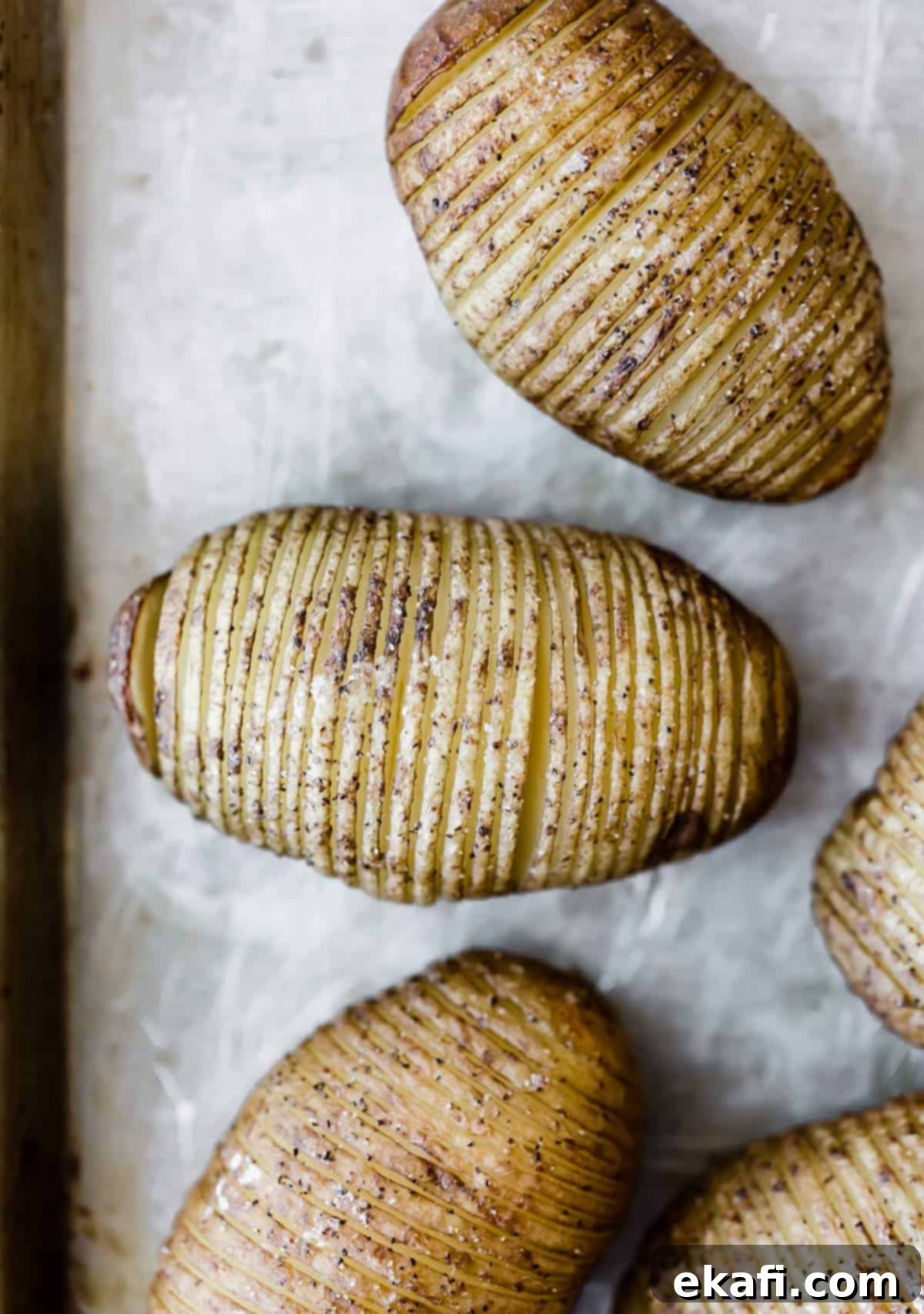 Crispy Air Fryer Hasselback Potatoes 4 Baked crispy Hasselback Potatoes on a gray baking sheet.