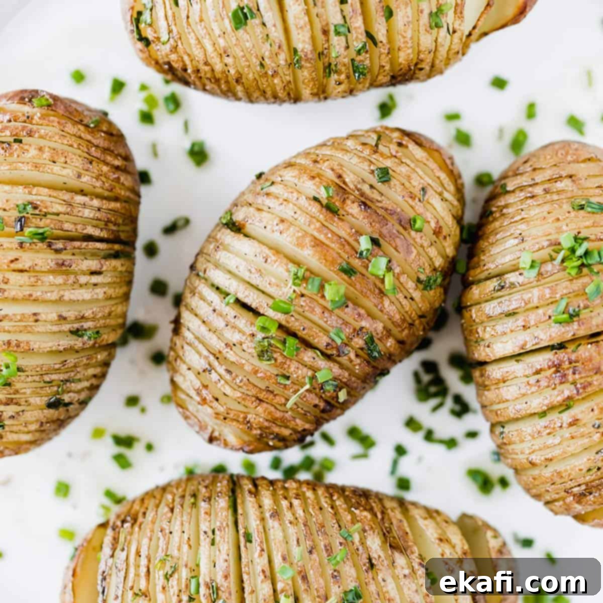 Crispy Air Fryer Hasselback Potatoes 5 Easy Hasselback Potatoes topped with fresh chives on a white background.