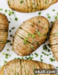 Crispy Air Fryer Hasselback Potatoes 7 Easy Hasselback Potatoes topped with fresh chives on a white background.