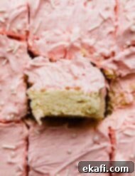 Frosted Sugar Cookie Bars 9 A Sugar Cookie Bar recipe cut into squares topped with pink frosting, a perfect treat.