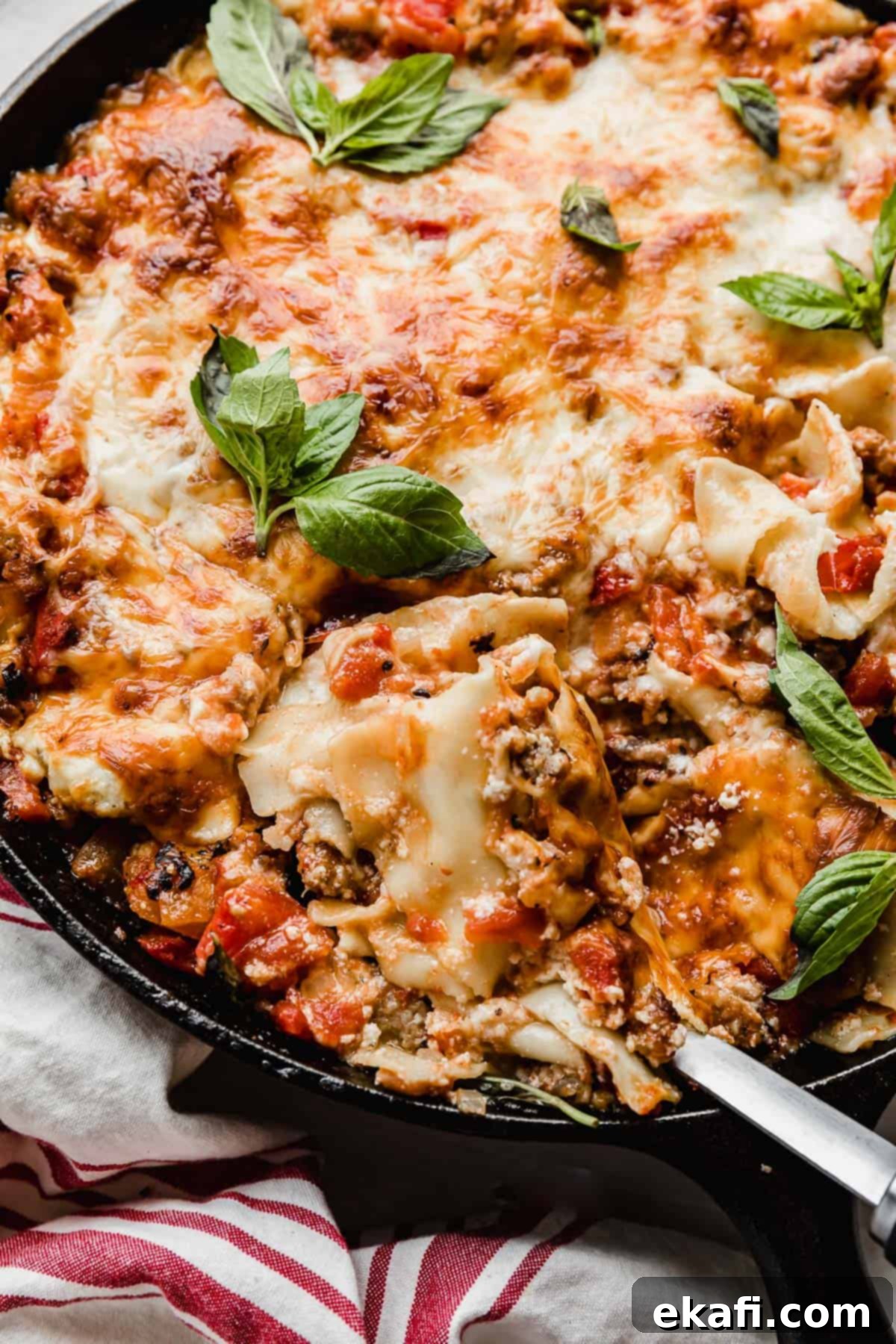 Rustic Cast Iron Lasagna 11 A spoon scooping out Cast Iron Lasagna from a skillet.