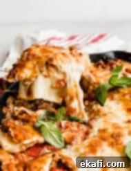 Rustic Cast Iron Lasagna 12 A spoon scooping out Cast Iron lasagna that has been topped with fresh basil.