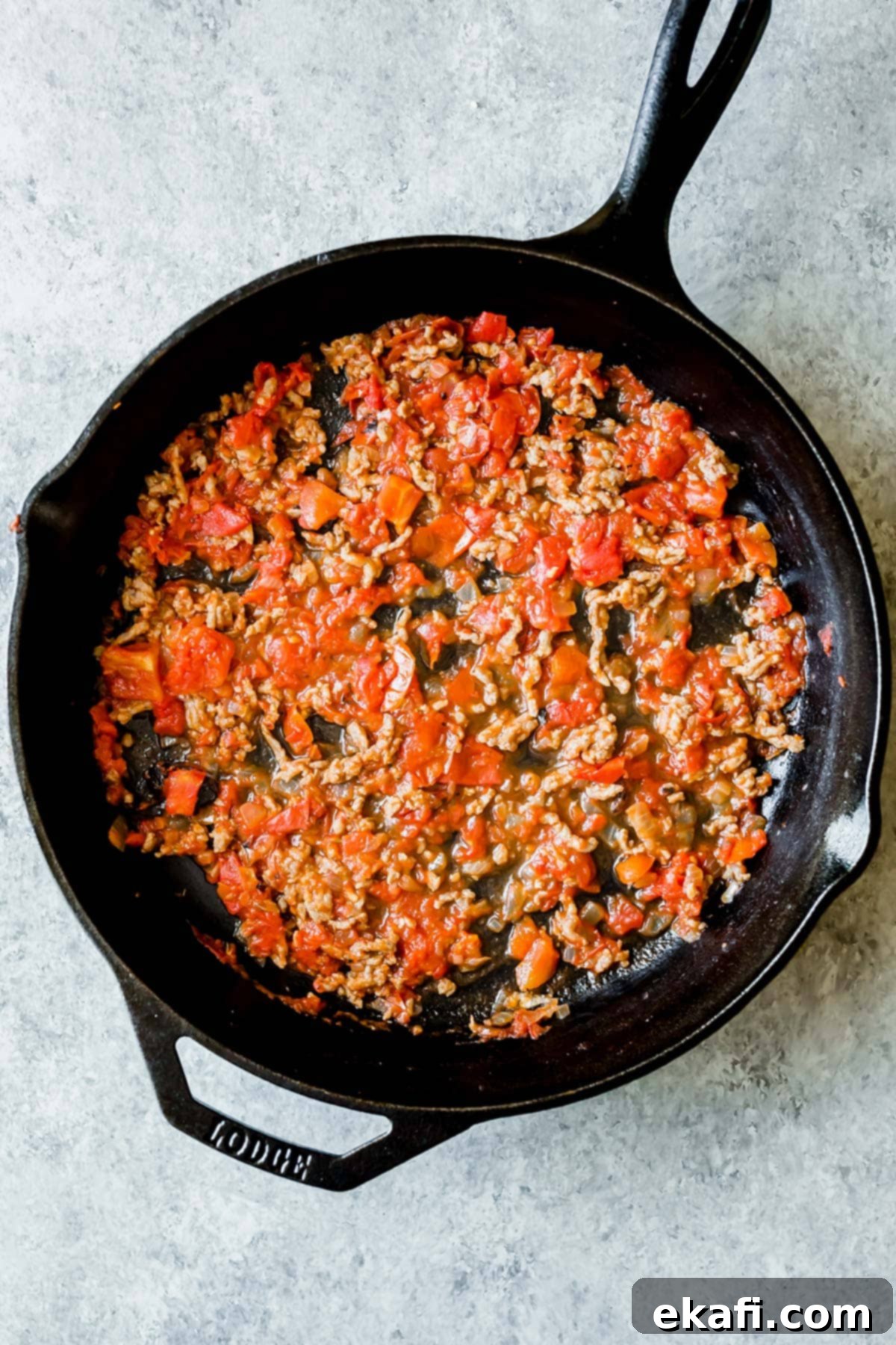 Rustic Cast Iron Lasagna 5 A cast iron skillet with a meat and tomato mixture spread along the bottom.