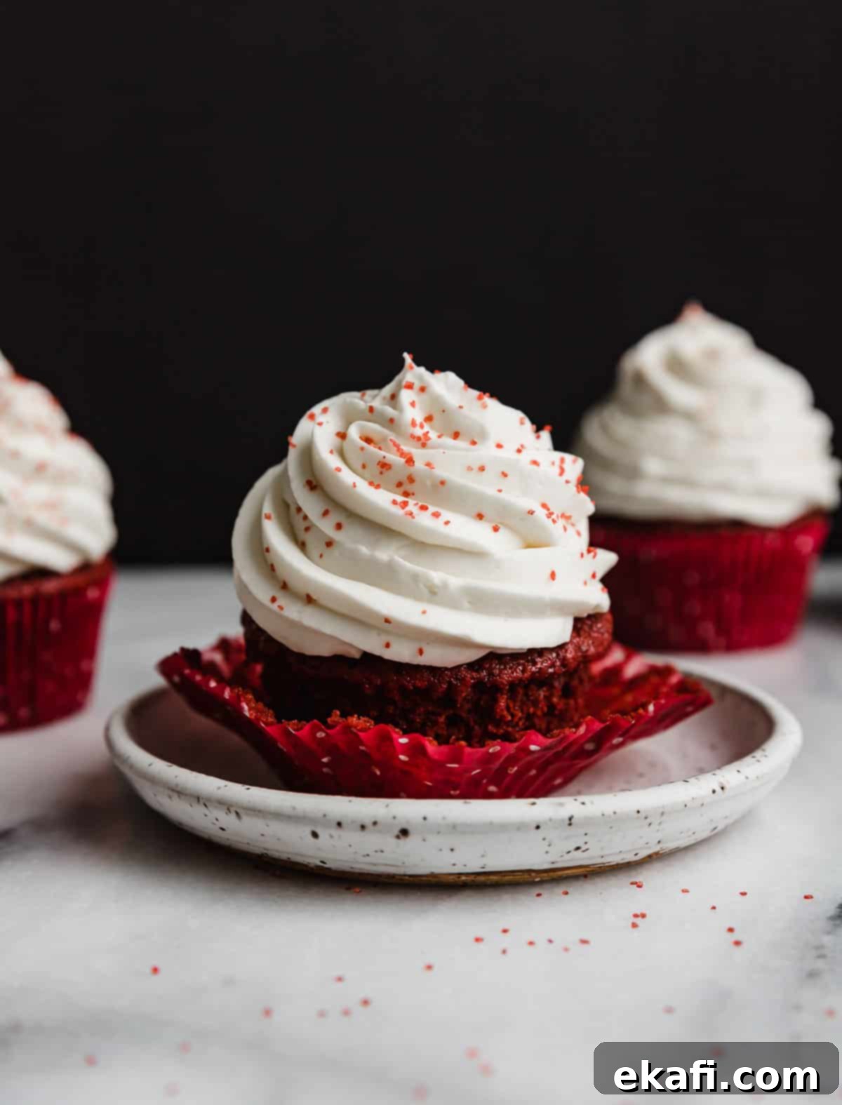 Crimson Velvet Delights 2 Red Velvet Cupcake on a white plate against a black background.
