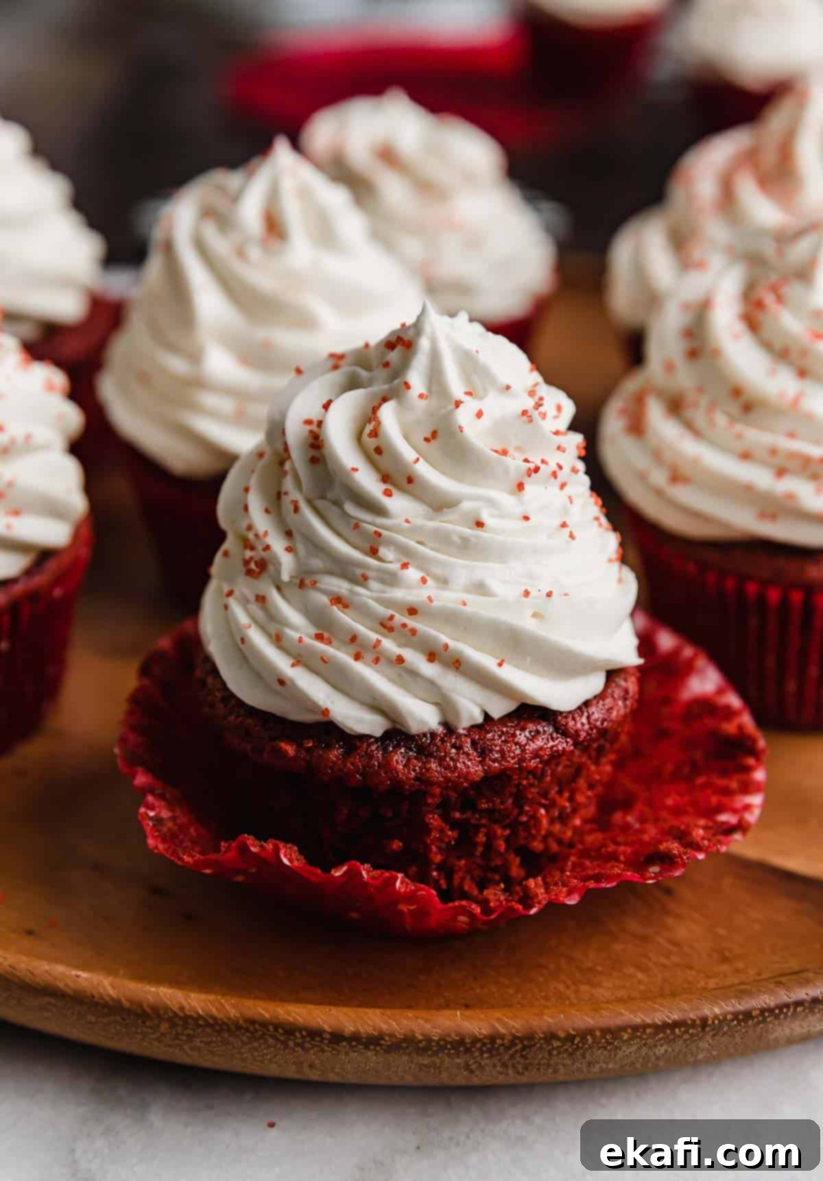 Crimson Velvet Delights 6 A Red Velvet Cupcake topped with cream cheese frosting, on a wooden plate.