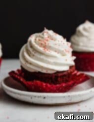 Crimson Velvet Delights 9 A red velvet cupcake topped with Cream Cheese Whipped Cream Frosting with red sugar sprinkles.