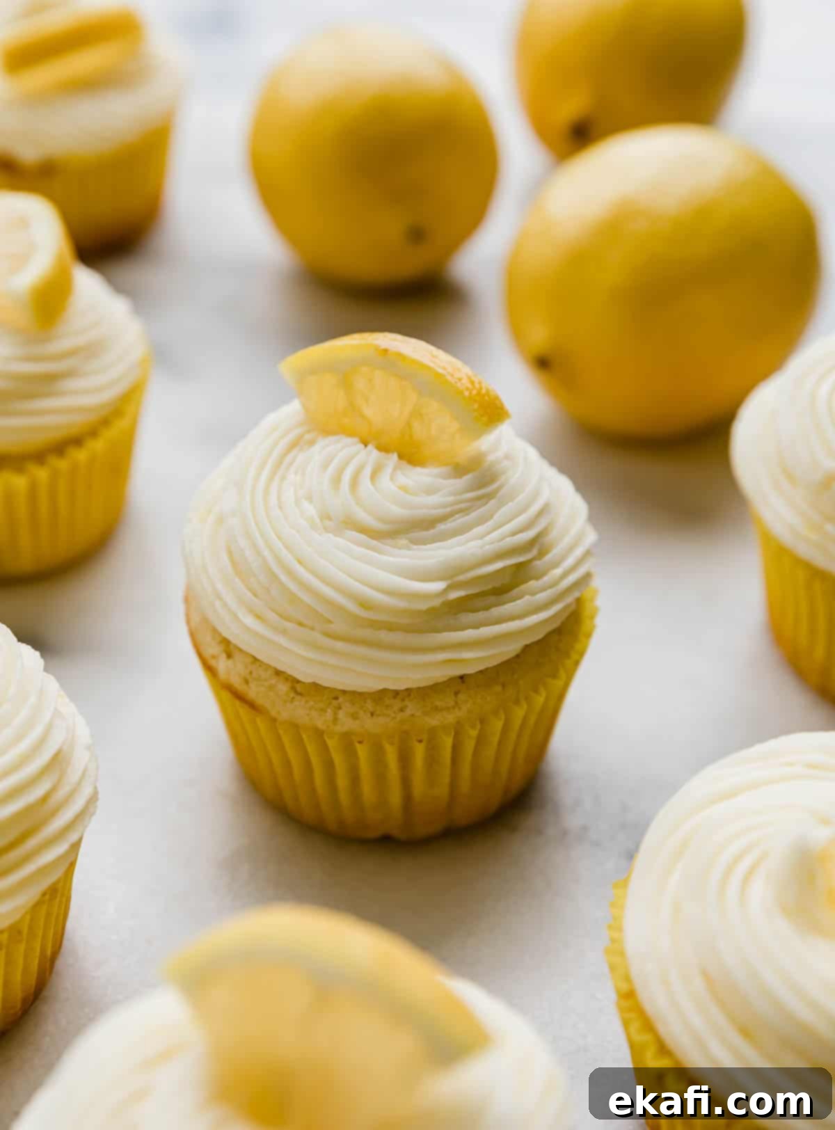 Zesty Lemon Cupcakes 8 Lemon cupcakes topped with Lemon Buttercream and a fresh lemon wedge on a white background.