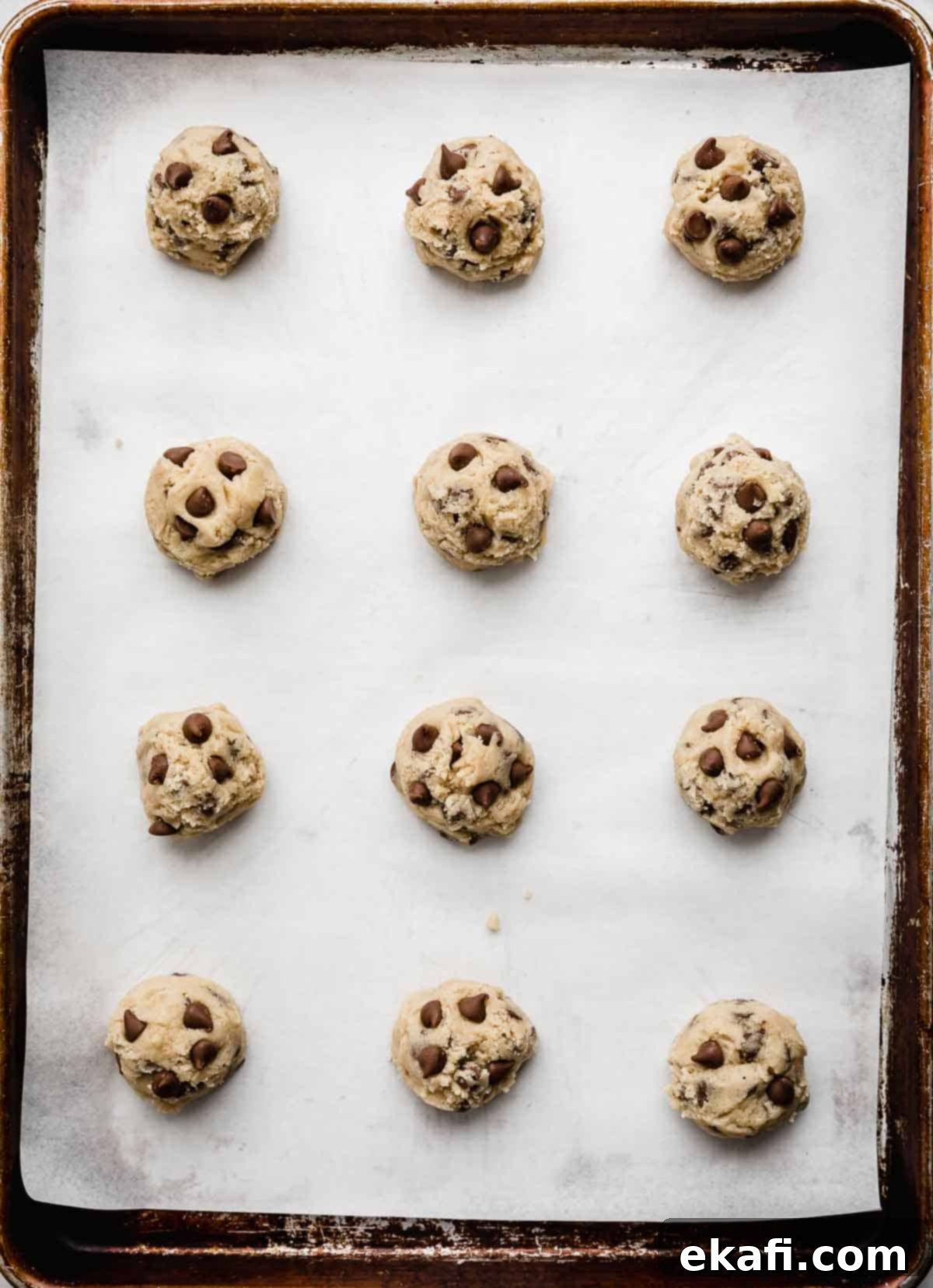 Irresistible Milk Chocolate Chip Cookies 5 Scooped Milk Chocolate Chip Cookie dough balls arranged on a white parchment-lined baking sheet, spaced for baking.