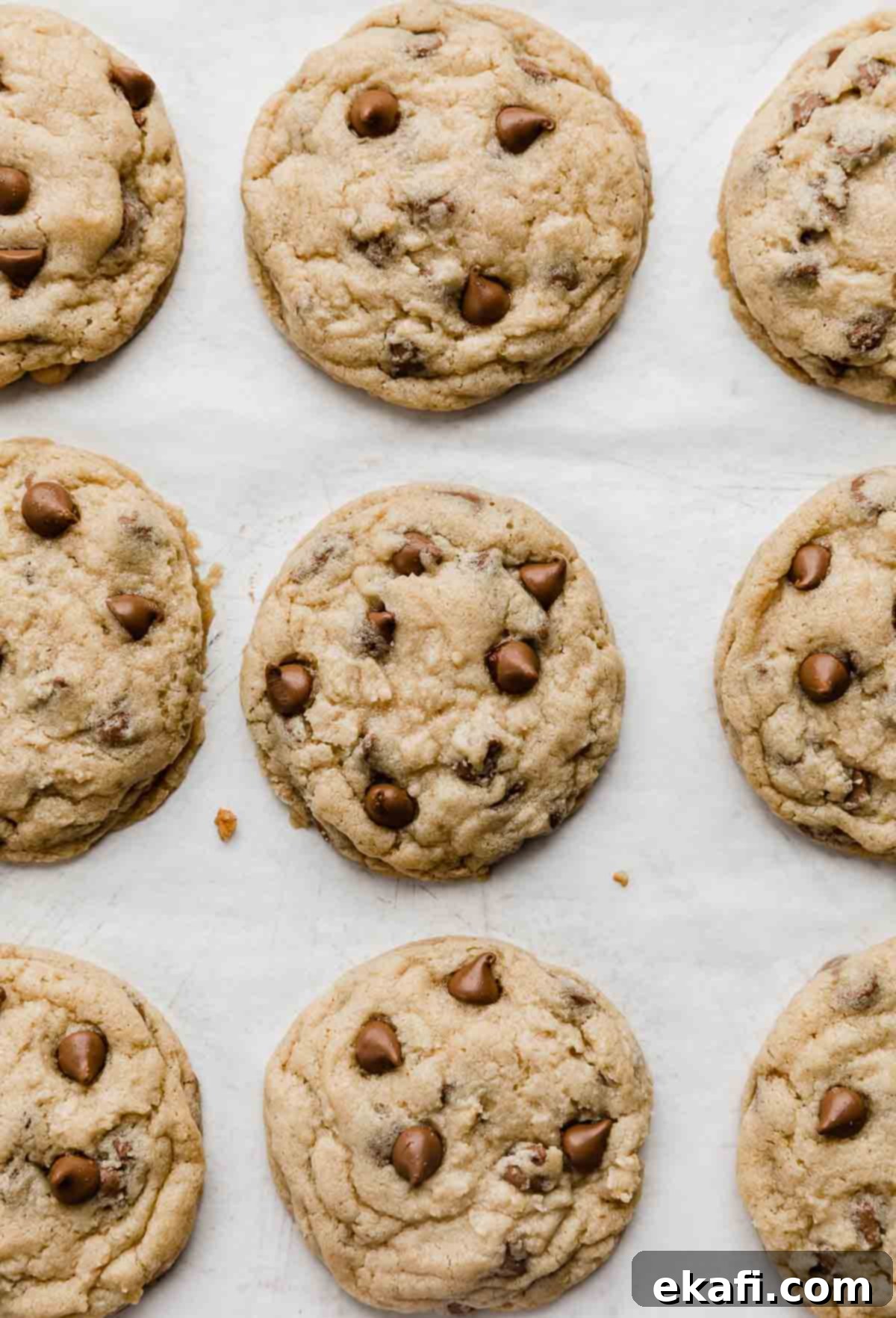 Irresistible Milk Chocolate Chip Cookies 6 Freshly baked Milk Chocolate Chip Cookies on white parchment paper, ready to be enjoyed.