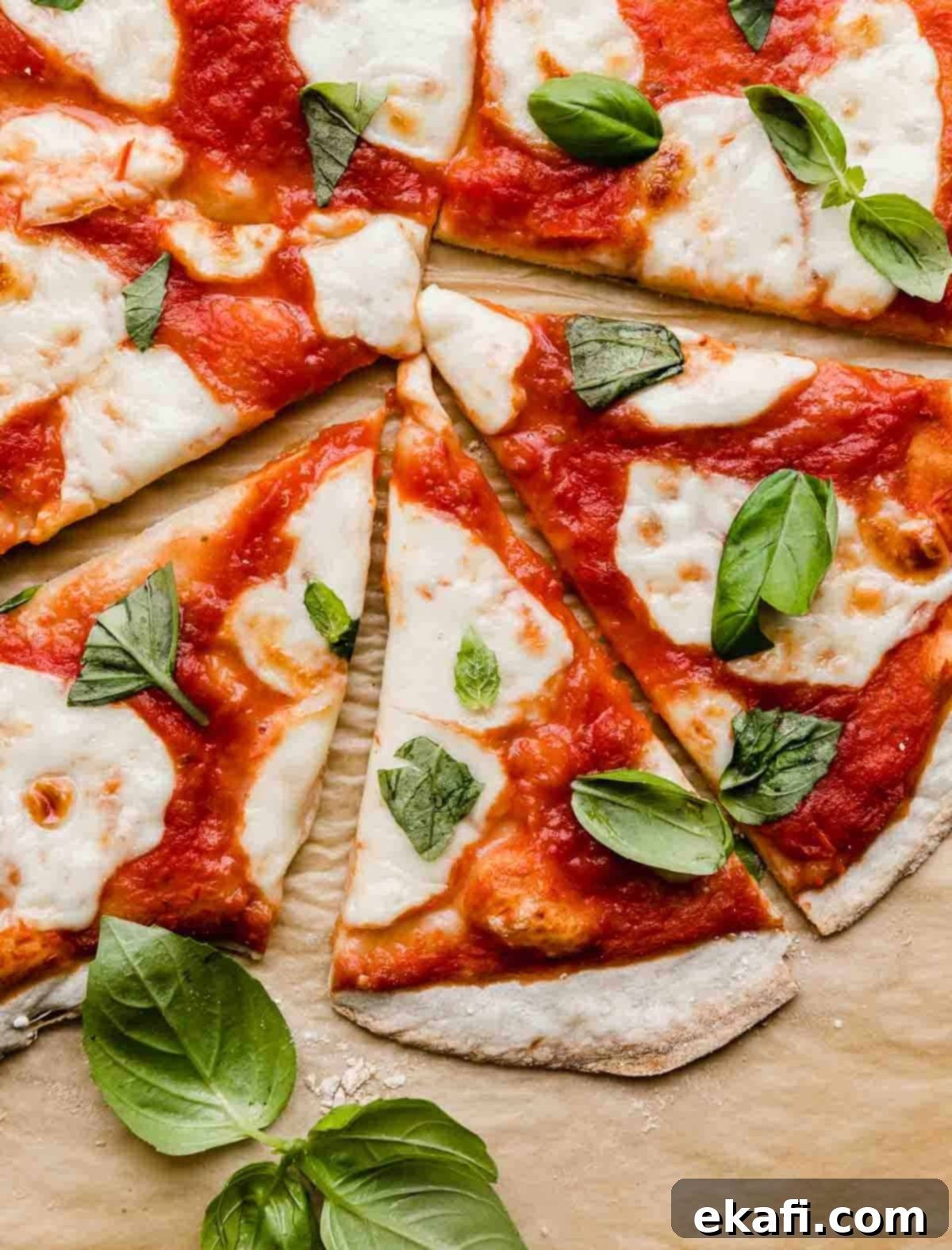 The Original Margherita Pizza 2 Several slices of Authentic Margherita Pizza topped with fresh basil on a Kraft parchment paper.