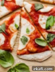 The Original Margherita Pizza 6 Authentic Margherita Pizza topped with fresh mozzarella and torn fresh basil on a light brown parchment paper.