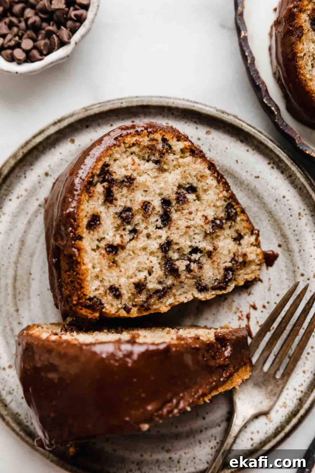 Rich Chocolate Chip Bundt Perfection 2 A slice of chocolate ganache covered Chocolate Chip Bundt Cake on a gray plate, showcasing its moist texture and rich glaze.