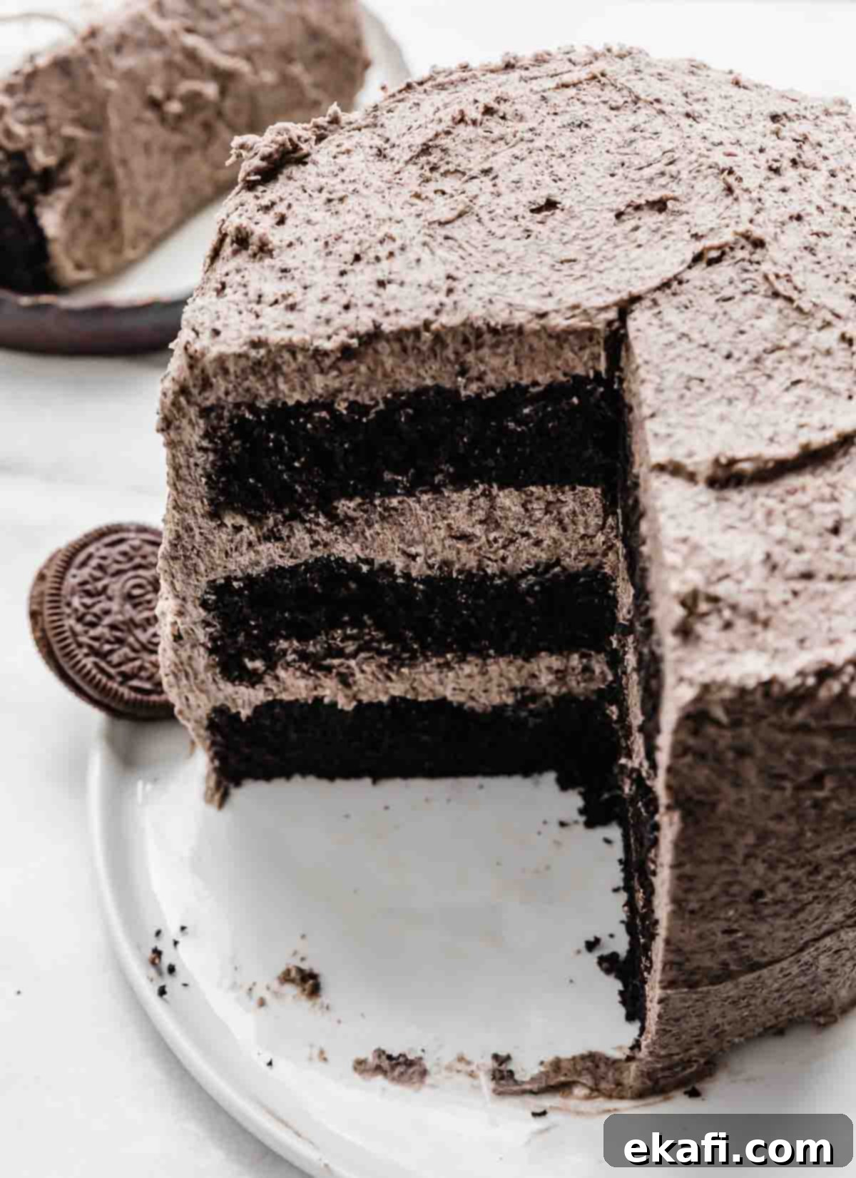 Decadent Oreo Dream 8 An Oreo Cake recipe on a white plate with a fourth of the cake cut from the main cake.