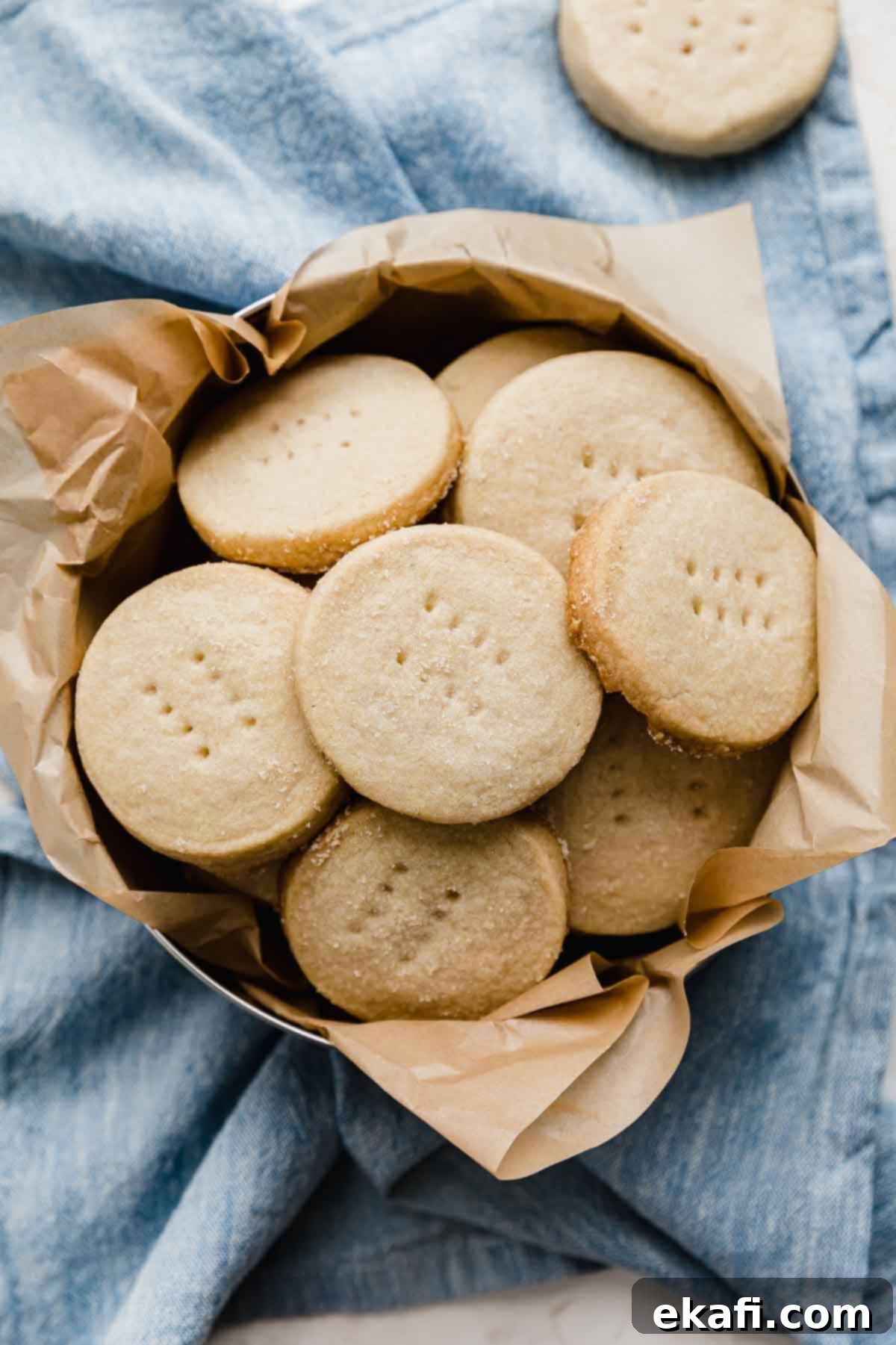 Grandma's Buttery Shortbread 8 Overhead photo of Grandma's Shortbread Cookies (cut into round circles) in a round tin on a light blue napkin.