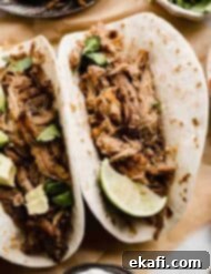 Carnitas 8 Mexican pulled pork inside a flour tortilla to make a carnitas, topped with avocado and a lime wedge.