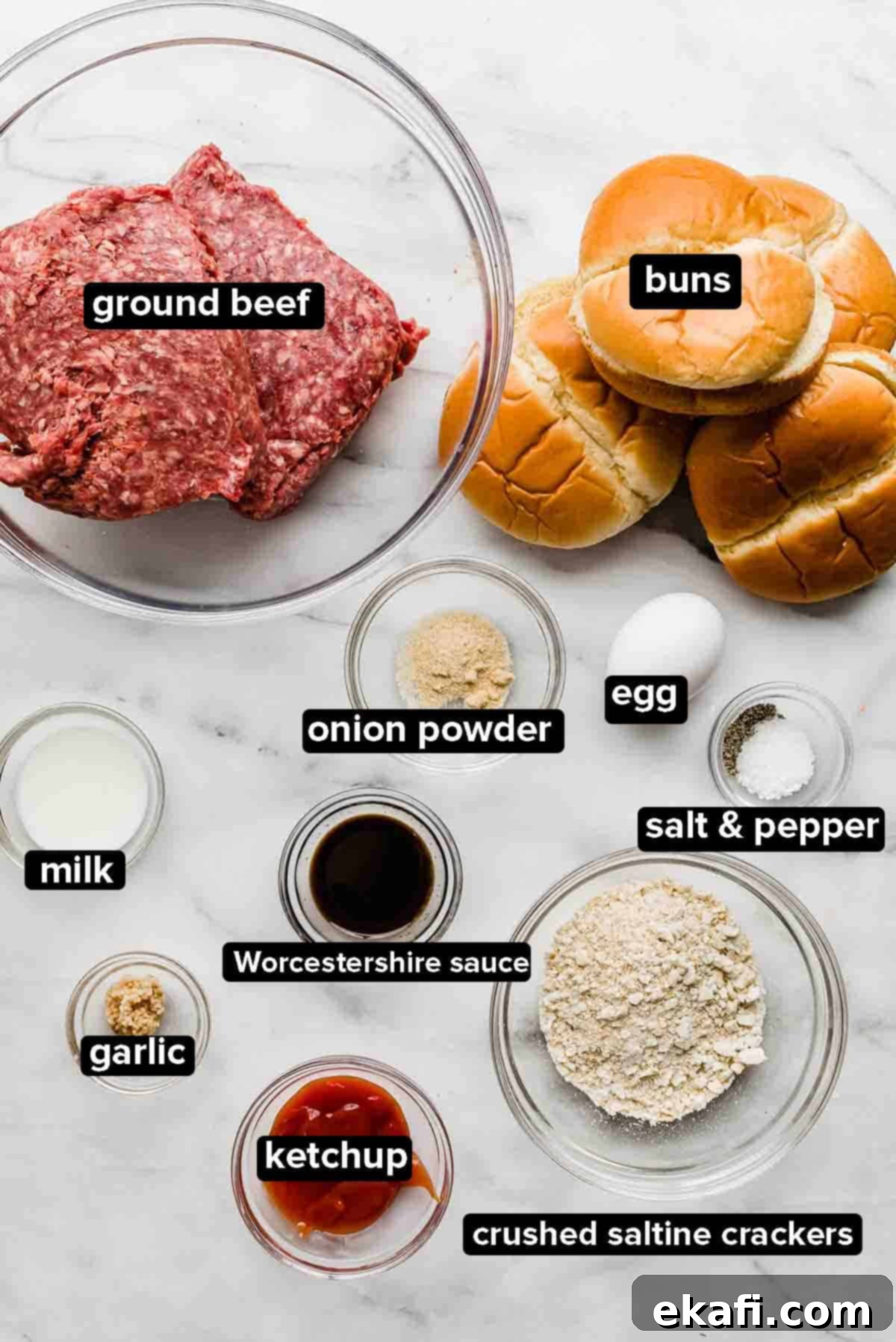 Μπέργκερ Μπριζόλας 3 Συστατικά για Steakhouse Burgers σε λευκό μαρμάρινο φόντο: κιμάς, ψωμάκια, κέτσαπ, σκόνη κρεμμυδιού, αυγό, αλάτι και πιπέρι, σκόρδο, γάλα και κράκερ αλμυρά.