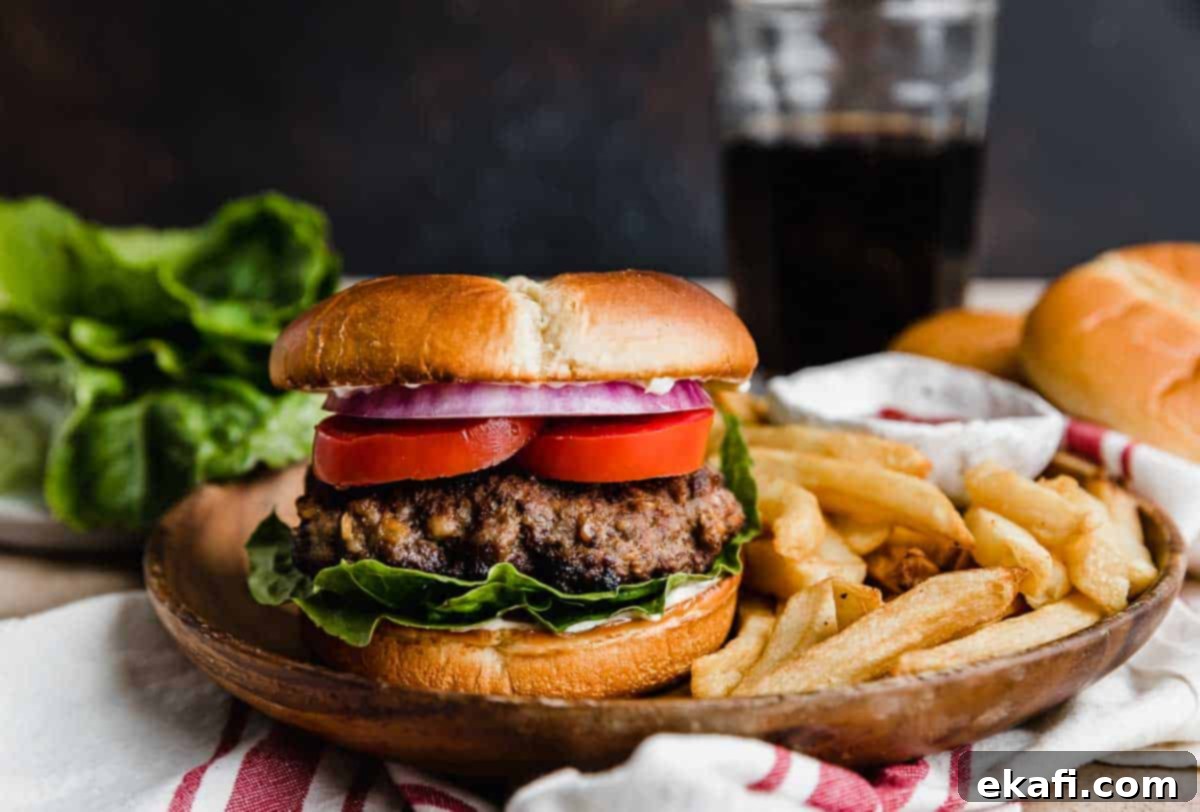 Μπέργκερ Μπριζόλας 5 Steakhouse Burgers σε καφέ πιάτο με τηγανητές πατάτες σε καφέ φόντο.