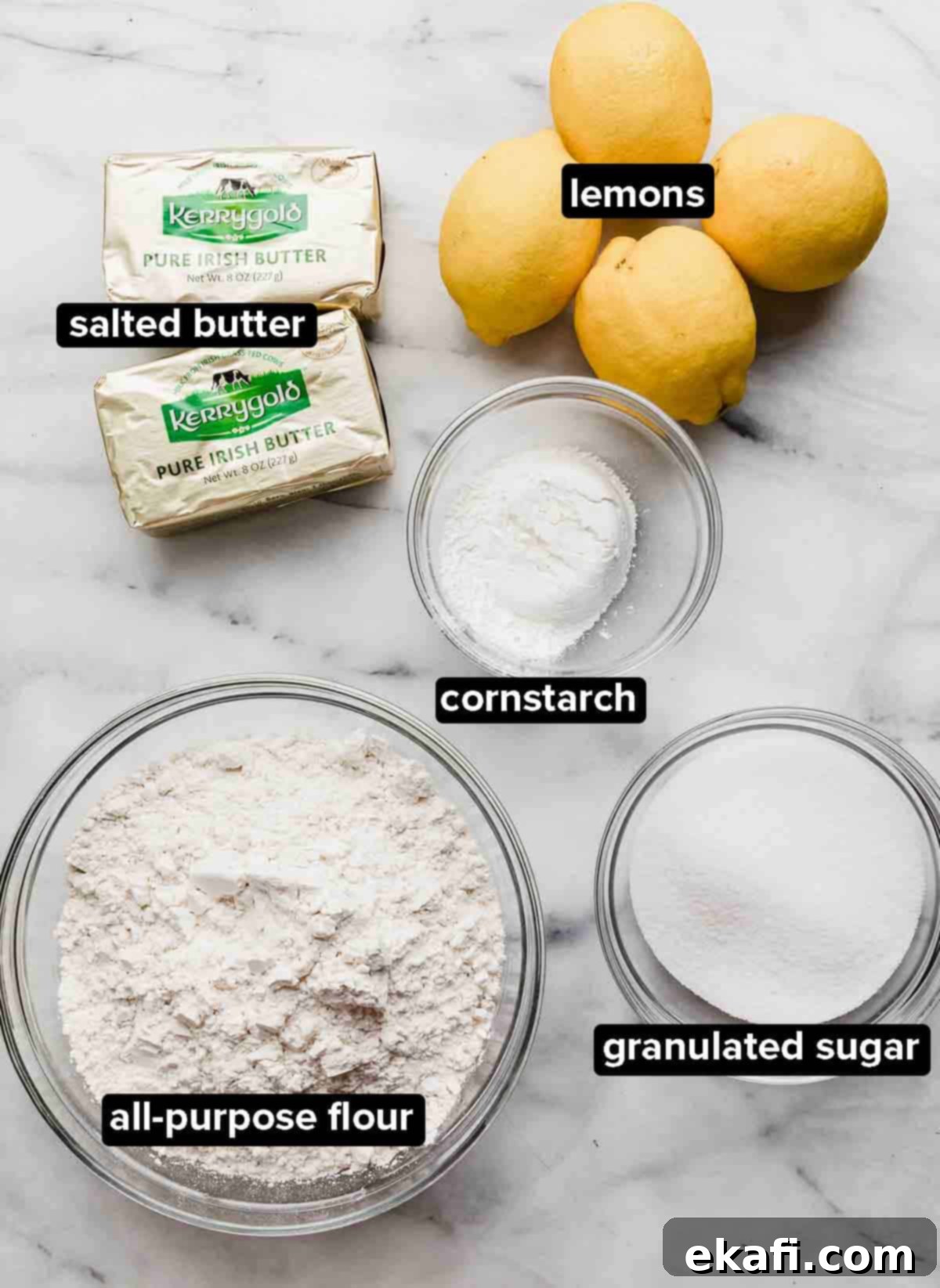 Sunshine Lemon Shortbread 3 Lemon Shortbread Cookies ingredients portioned into glass bowls on a white and gray marble background: butter, flour, lemons, cornstarch.