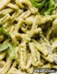 Vibrant Avocado Pesto Pasta 6 A close up image of pasta tossed in a light green basil pesto with mashed avocado and topped with fresh basil leaves.