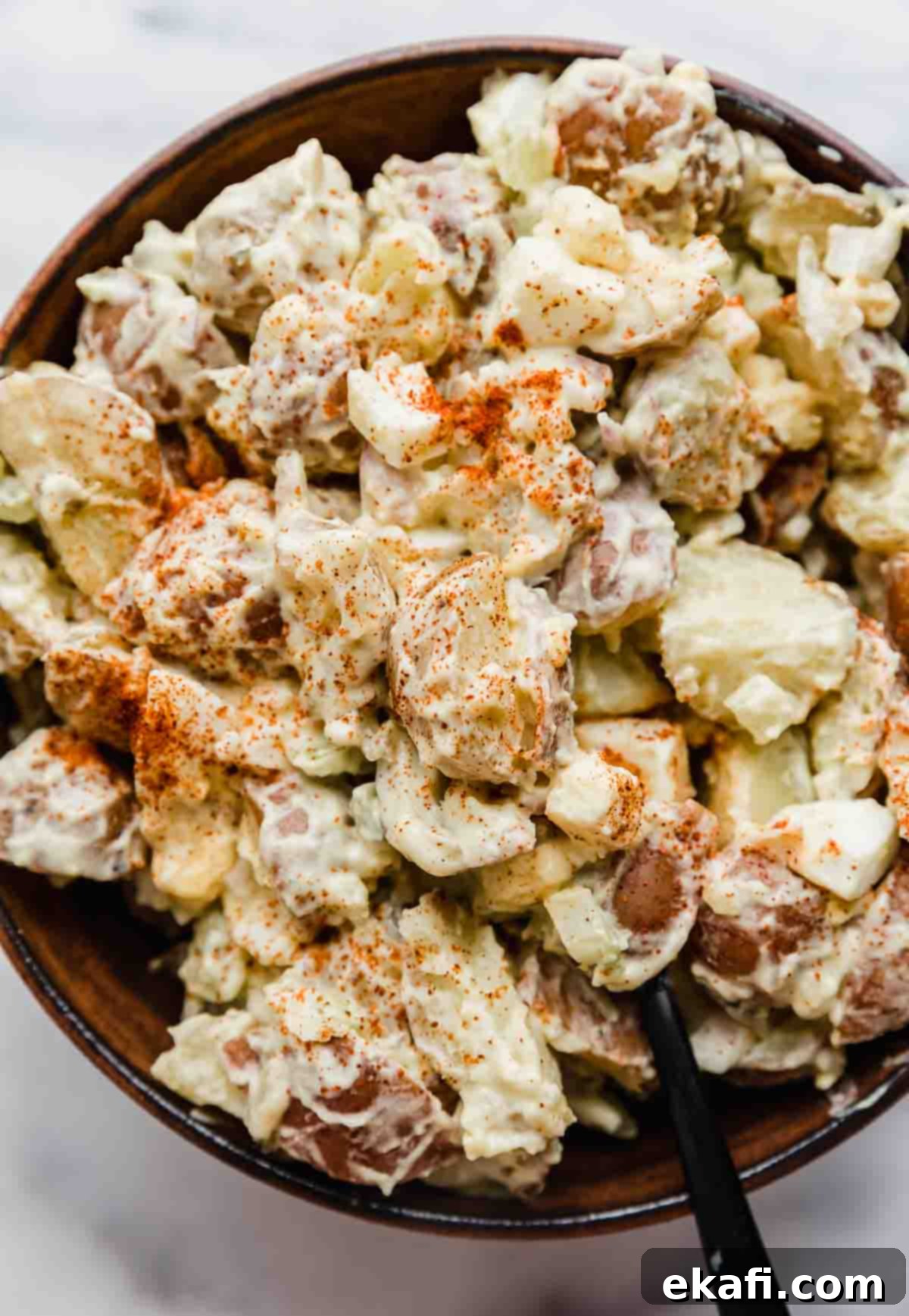 Homestyle Baby Potato Salad 6 Paprika topped baby potato salad recipe in a bowl on a white background.