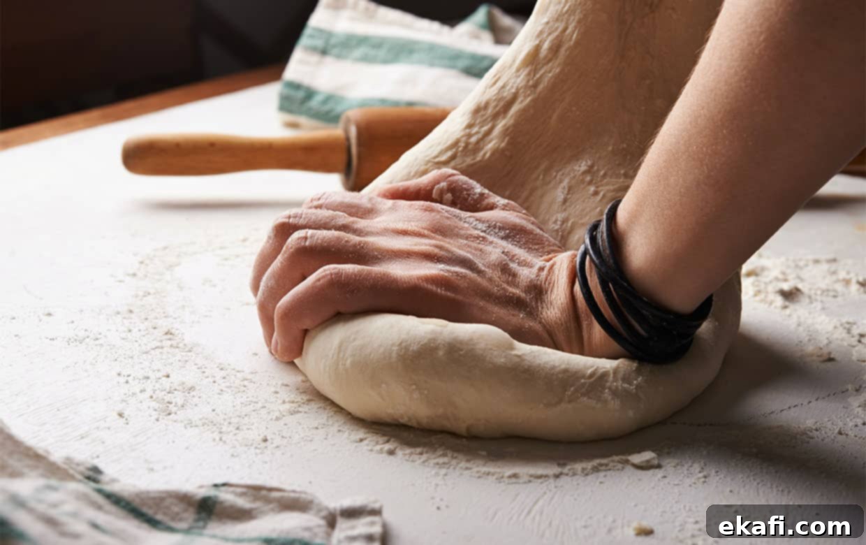 Flawless Pizza Dough Every Time 2 Hands kneading homemade pizza dough on a wooden surface.
