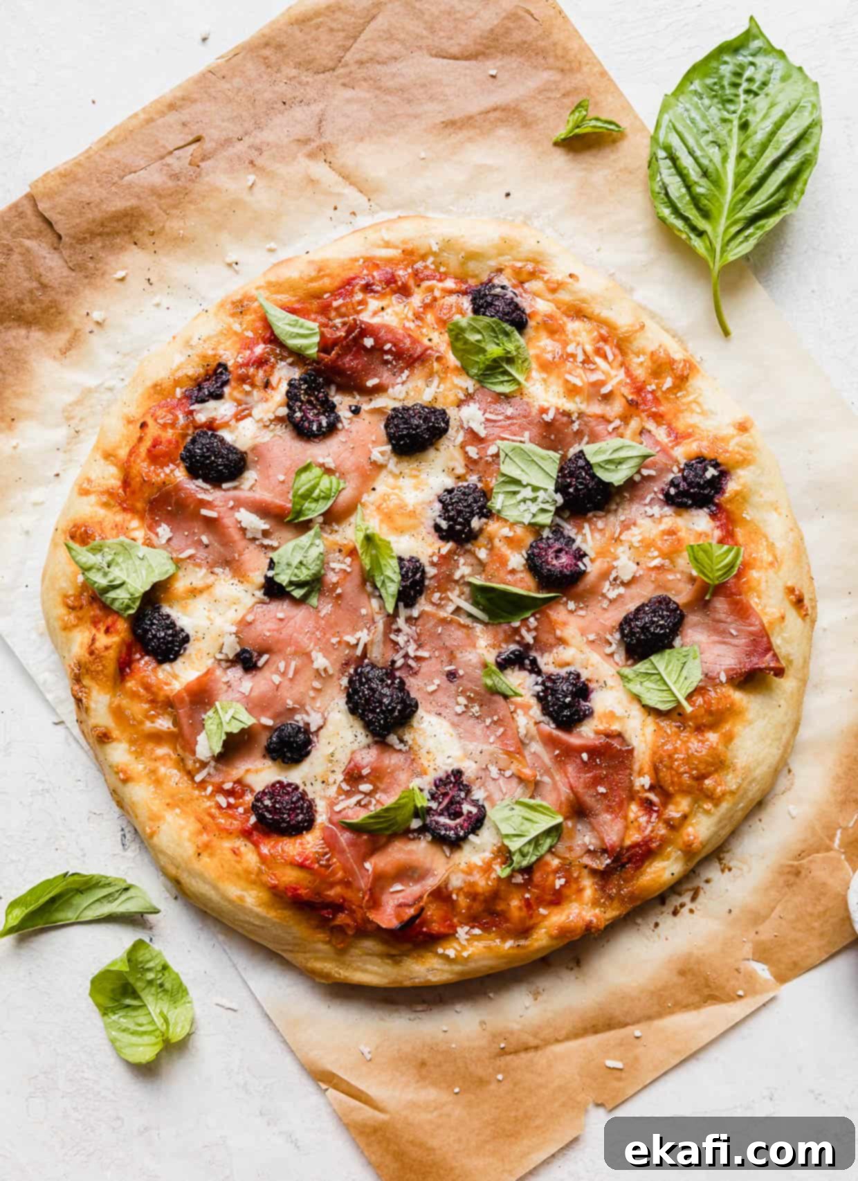 Flawless Pizza Dough Every Time 6 Blackberry pizza topped with fresh basil and prosciutto on brown parchment paper.
