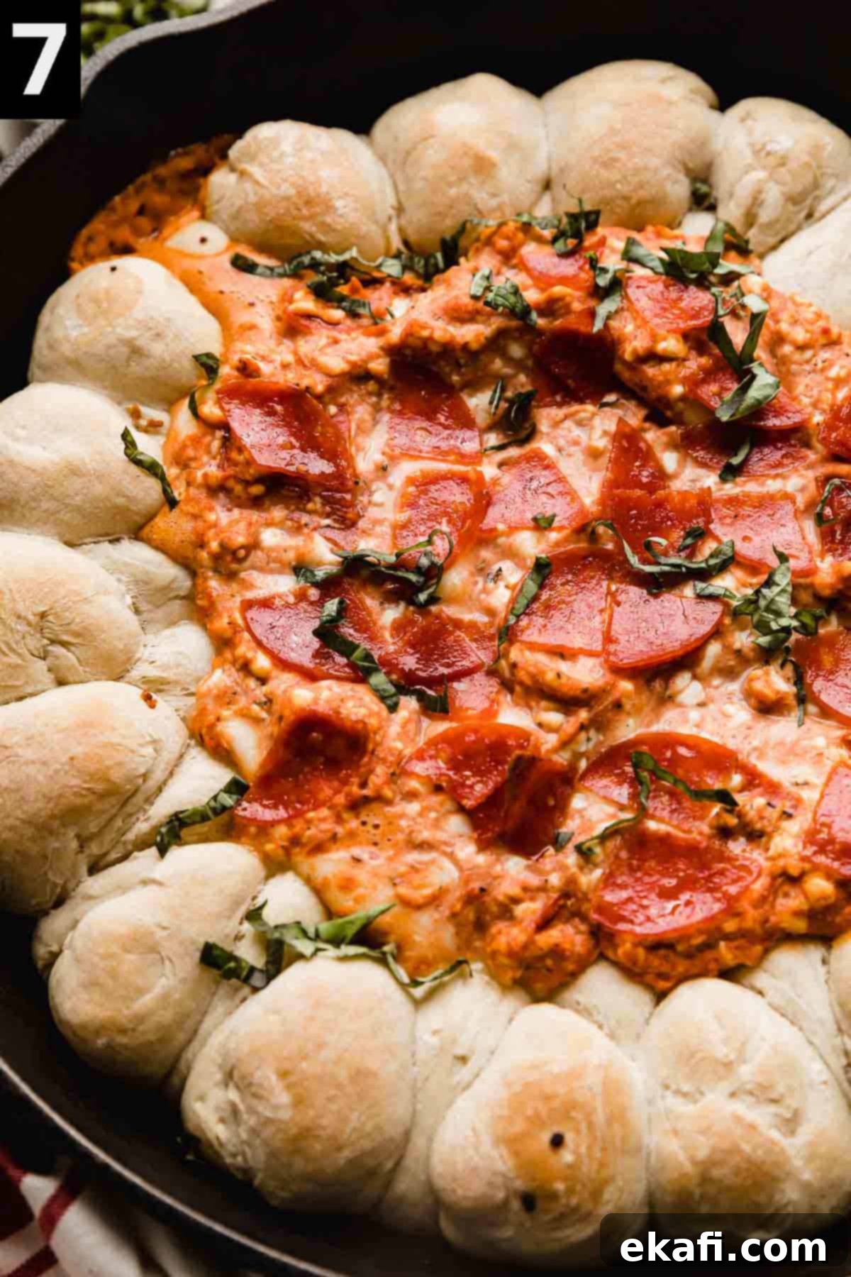 Ultimate Pepperoni Pizza Dip 5 A close-up image of a freshly baked, bubbling Pepperoni Pizza Dip in a cast iron skillet, generously topped with melted cheese, crispy pepperoni, and vibrant fresh basil leaves.