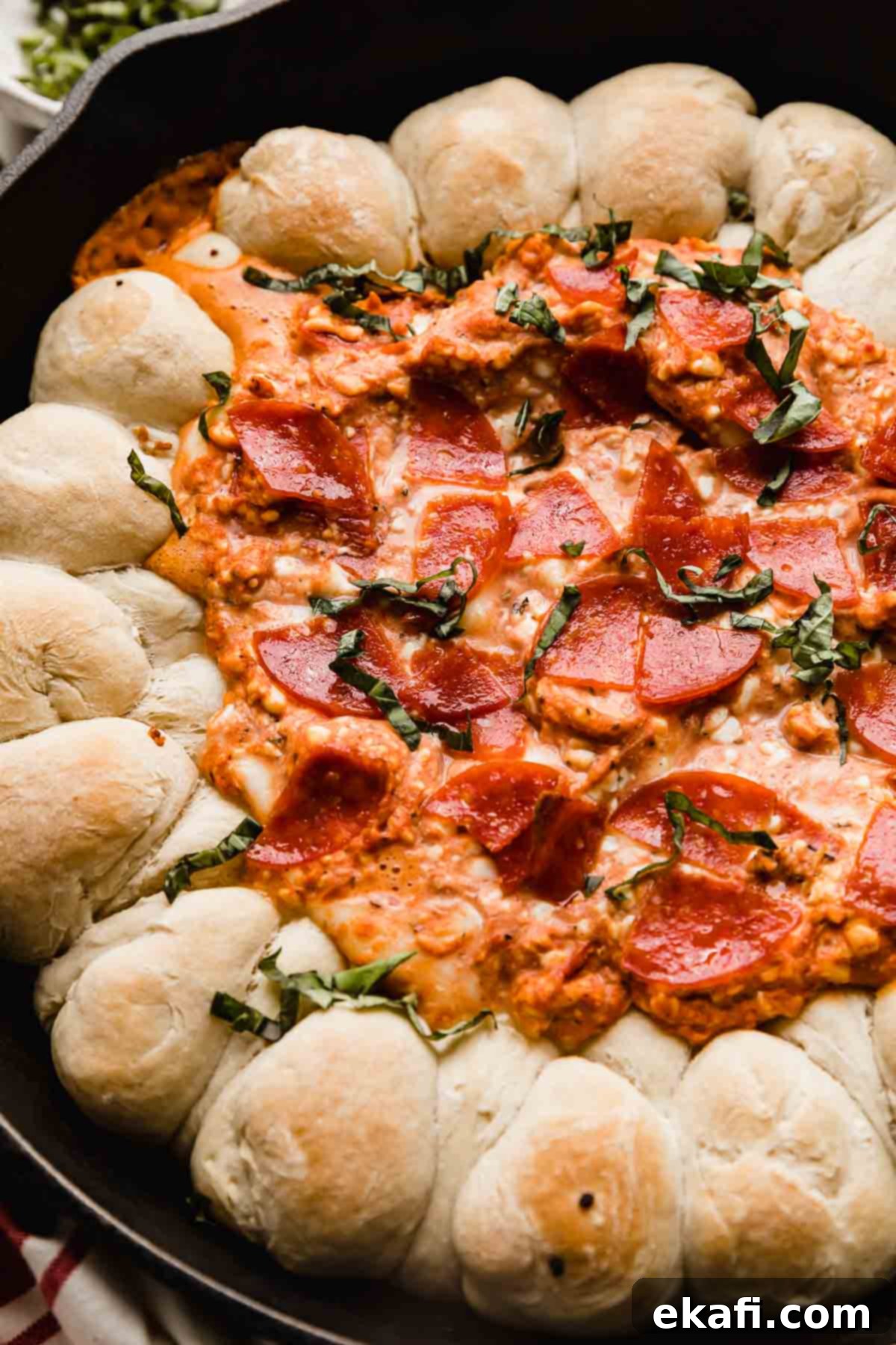 Ultimate Pepperoni Pizza Dip 7 Creamy cheese pizza dip topped generously with pepperoni and fresh basil, set invitingly in a cast iron skillet, ready to be enjoyed as a shared appetizer.
