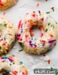 Confetti Delights 7 A Sprinkle Donut on a white background, the funfetti donut topped with glaze and extra sprinkles.