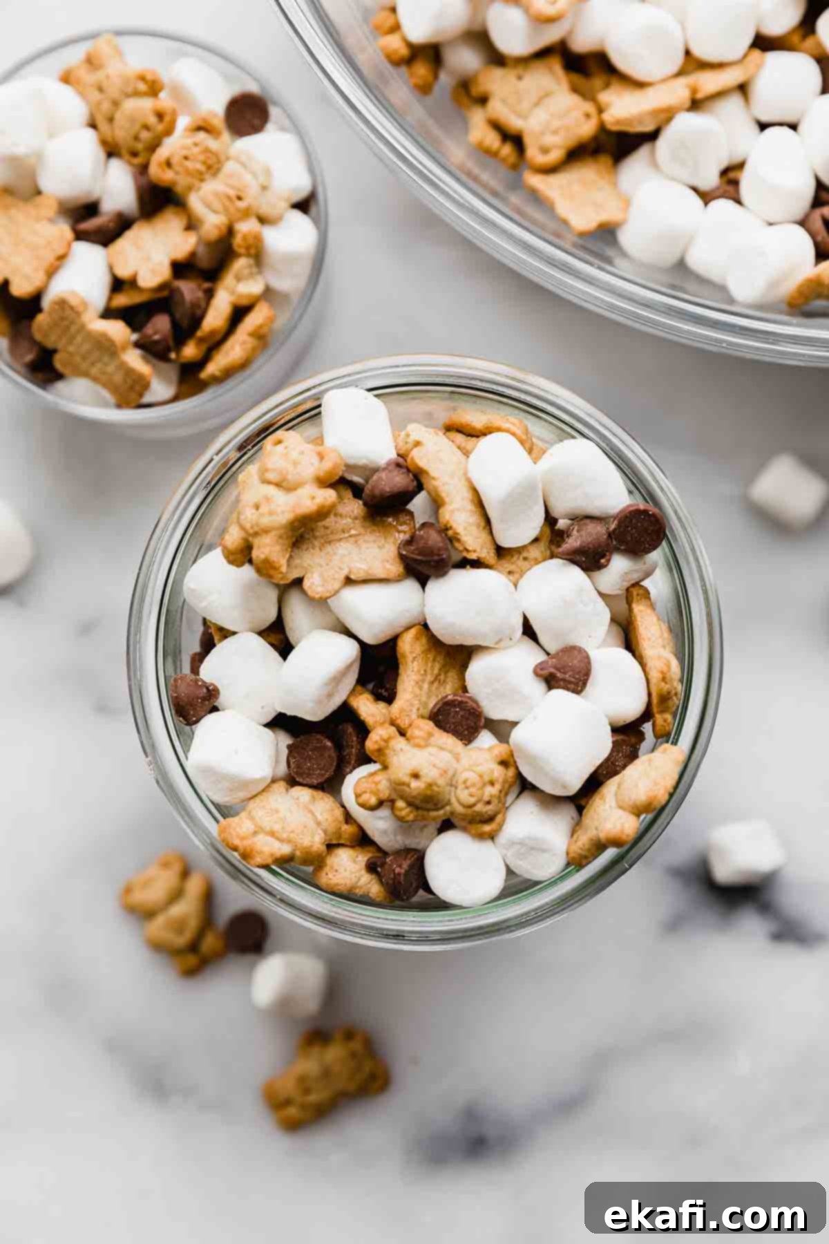 S'mores Mix 2 S'mores Mix in a glass cup on a white marble background, the S'mores trail mix consists of mini marshmallows, teddy grahams, and milk chocolate chips.