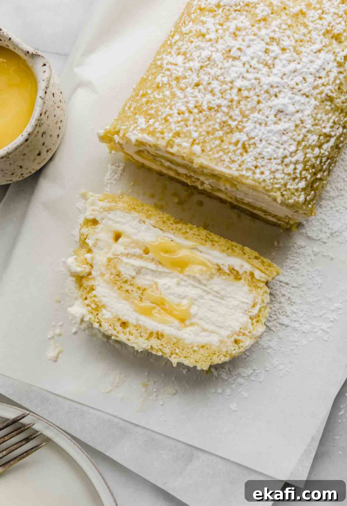 Ρολό λεμονιού 2 Μια φέτα Lemon Swiss Roll γεμάτη με κρέμα μασκαρπόνε και λεμονόκρεμα, σε λευκό χαρτί ψησίματος.