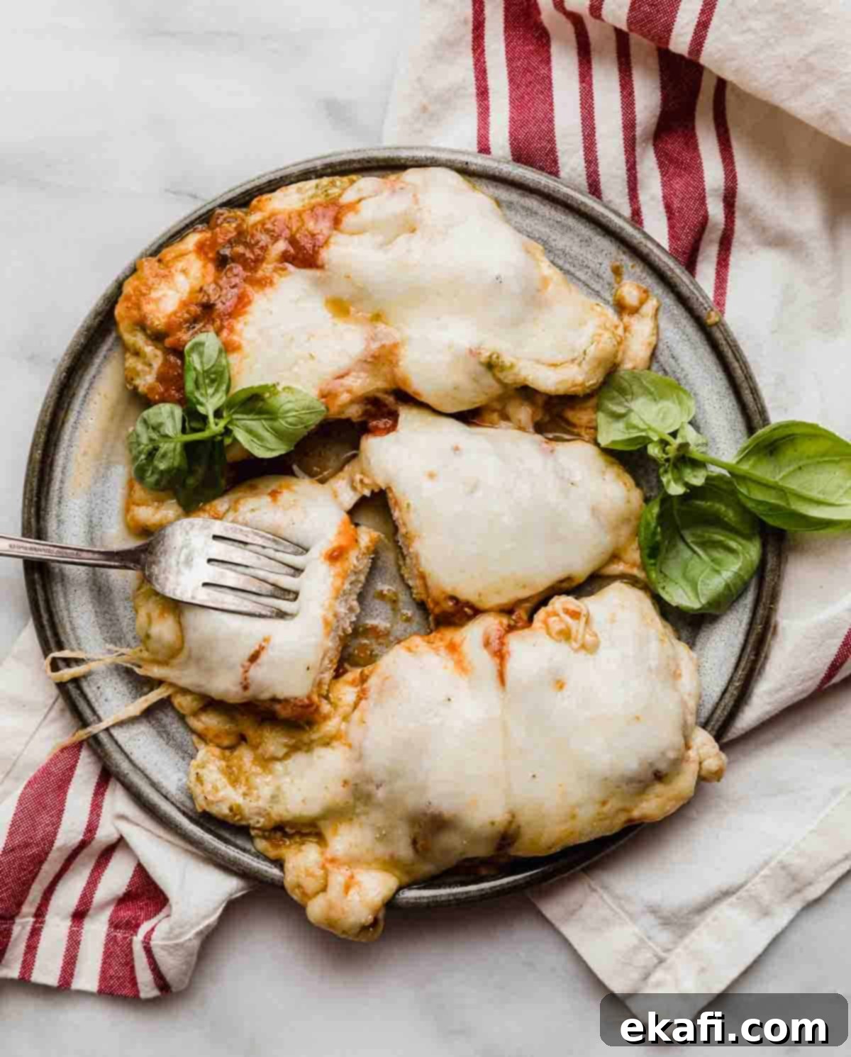 Pesto Parmesan Chicken 5 A gray plate topped with 3 pieces of Pesto Chicken Parmesan.