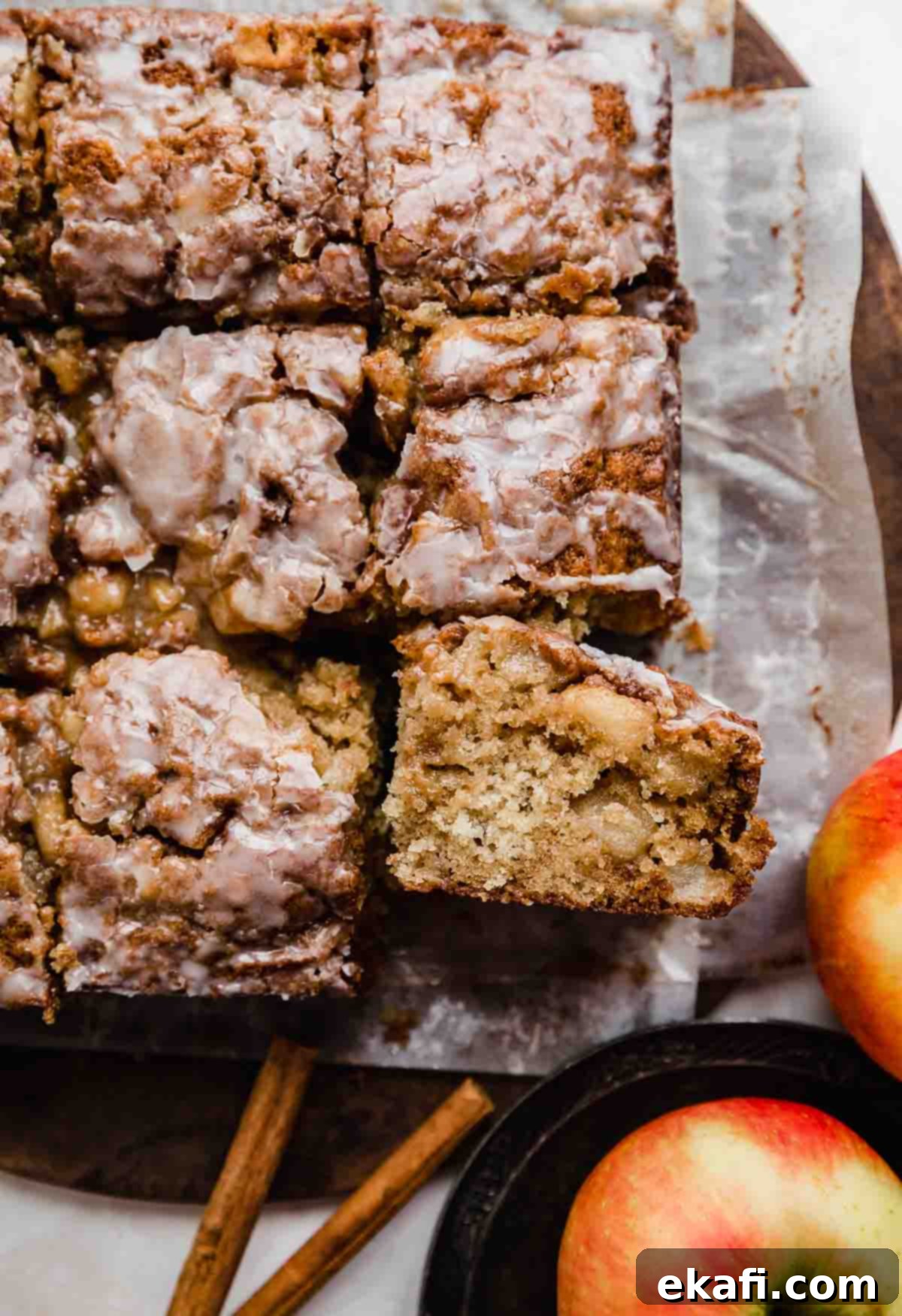 Baked Apple Fritter Delight 2 An Apple Fritter Cake sliced into squares on parchment paper, showcasing its moist texture and apple chunks.