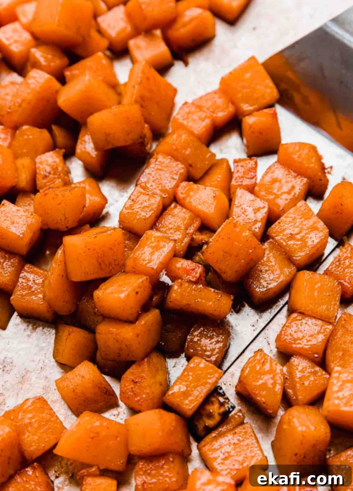 This Cinnamon Roasted Butternut Squash will be your new favorite fall side dish. The butternut squash melts in your mouth! Cinnamon Roasted Butternut Squash on a baking sheet, golden brown and glazed.