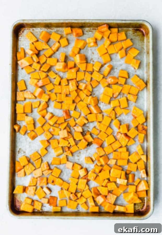 This Cinnamon Roasted Butternut Squash will be your new favorite fall side dish. The butternut squash melts in your mouth! Diced butternut squash on a baking sheet, ready for seasoning.