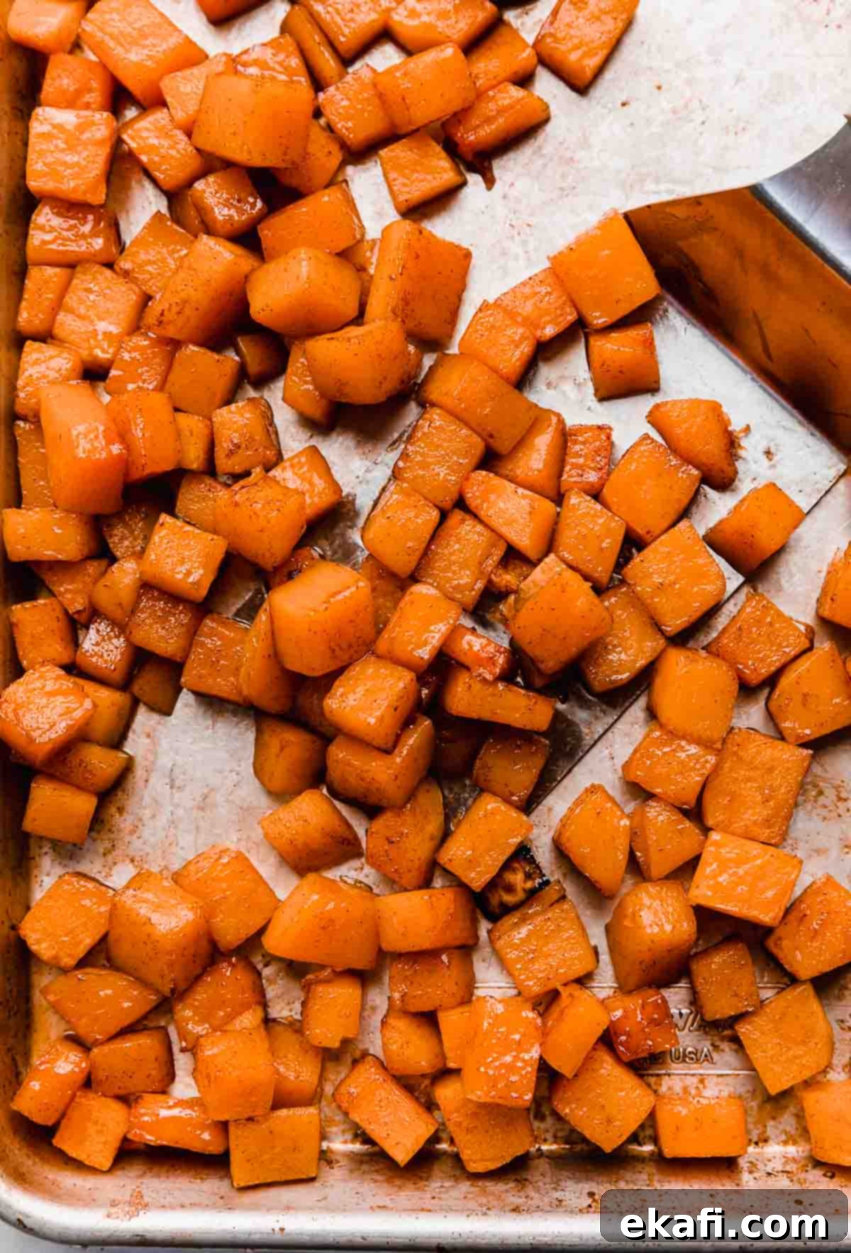 This Cinnamon Roasted Butternut Squash will be your new favorite fall side dish. The butternut squash melts in your mouth! Cinnamon Roasted Butternut Squash on a baking sheet, glistening with glaze.