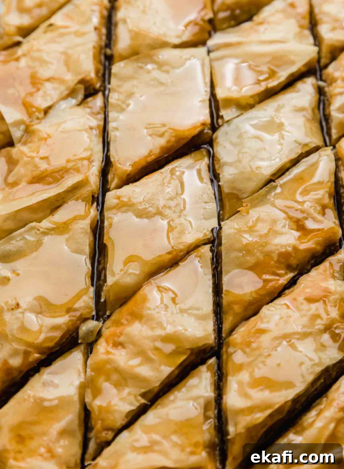 Authentic Greek Baklava 7 A close-up shot of golden crispy Greek Baklava, cut into perfect diamond shapes in its baking pan, generously covered with glistening honey syrup.