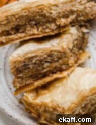 Authentic Greek Baklava 9 Three perfectly baked Greek Baklava pastries, glistening with honey syrup, arranged on a white plate, ready to be served.