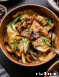 Πικάντικα Γουόντον Κοτόπουλου 7 Πικάντικα Wontons Κοτόπουλου σε καφέ μπολ με ένα κουτάλι να παίρνει ένα wonton.