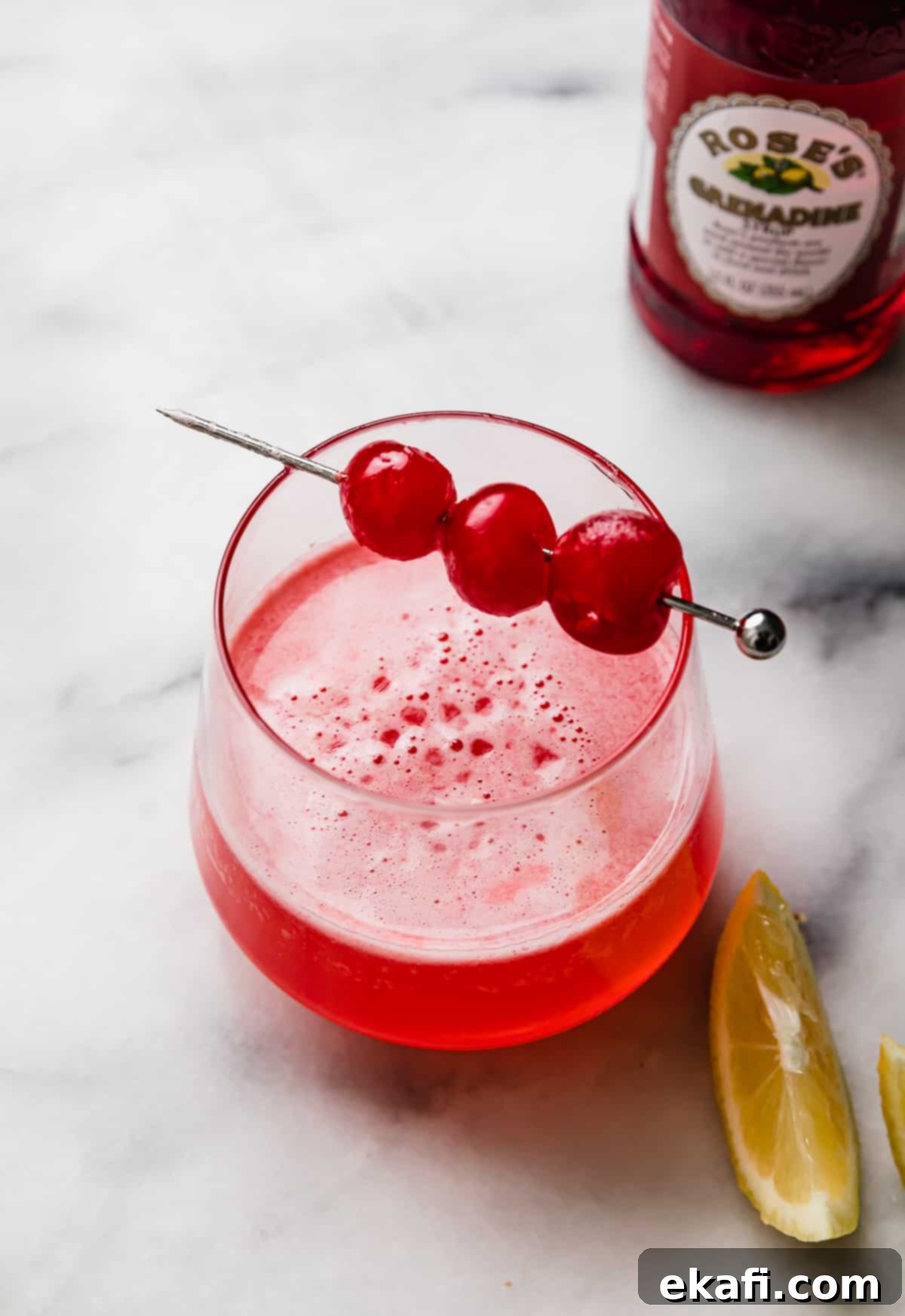 Pink Lady Bliss 5 Pink Lady Mocktail in a small glass with three maraschino cherries on a cocktail stick.