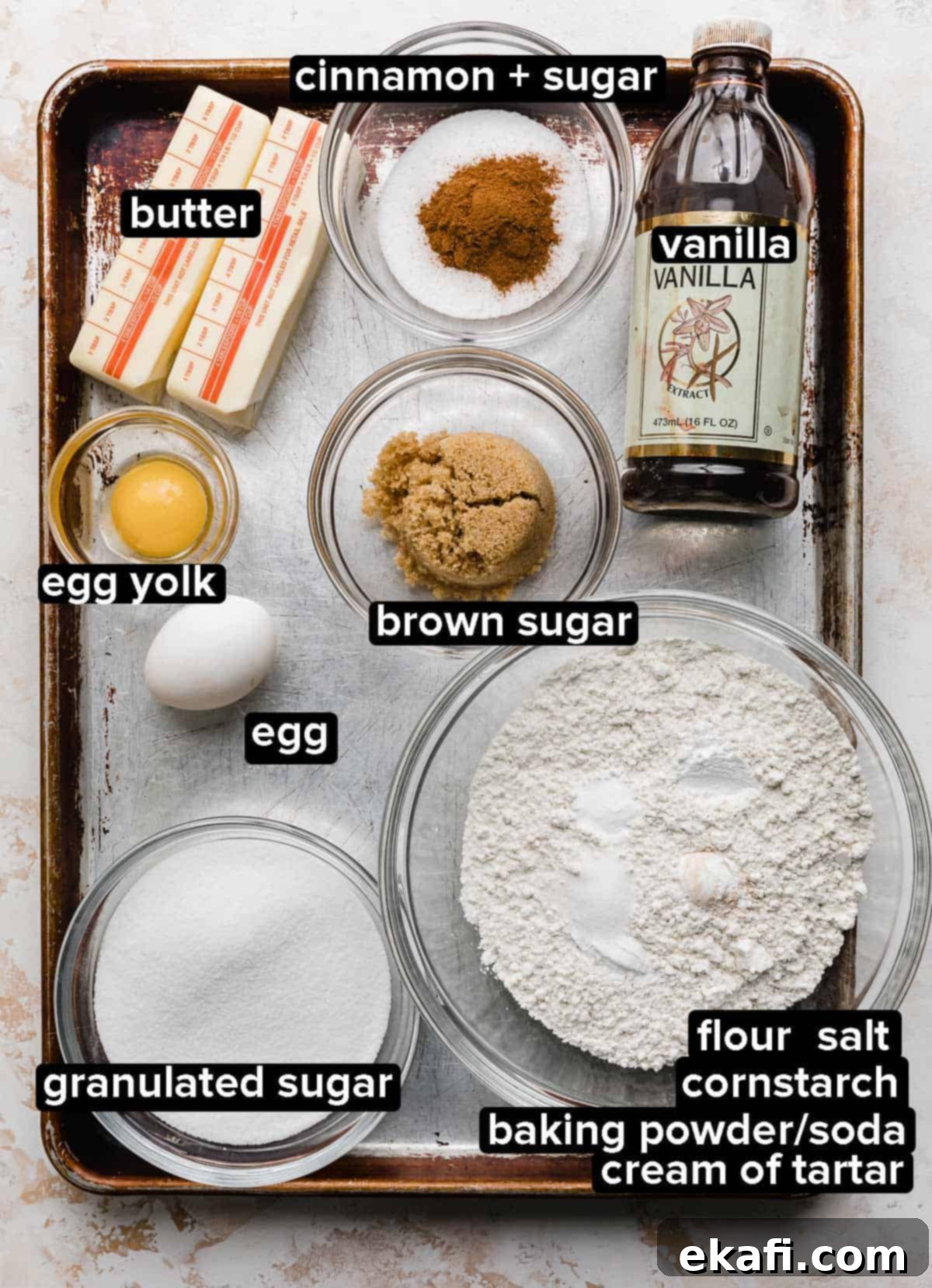 Chewy Snickerdoodle Blondies 3 Snickerdoodle Bar ingredients on a baking sheet, each ingredients portioned into glass bowls: butter, egg, yolk, sugar, cinnamon, vanilla, flour, cream of tartar, and leavening agents.