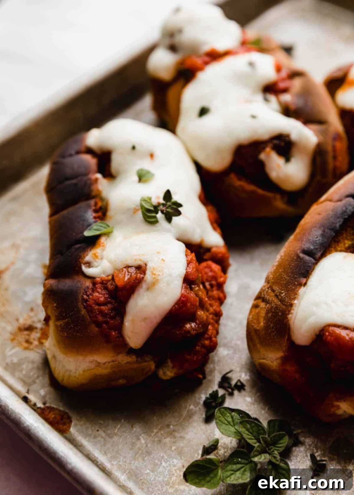 Classic Italian Meatball Subs 2 Italian Meatball Subs topped with melty mozzarella cheese and a garnish of fresh oregano on a baking sheet.