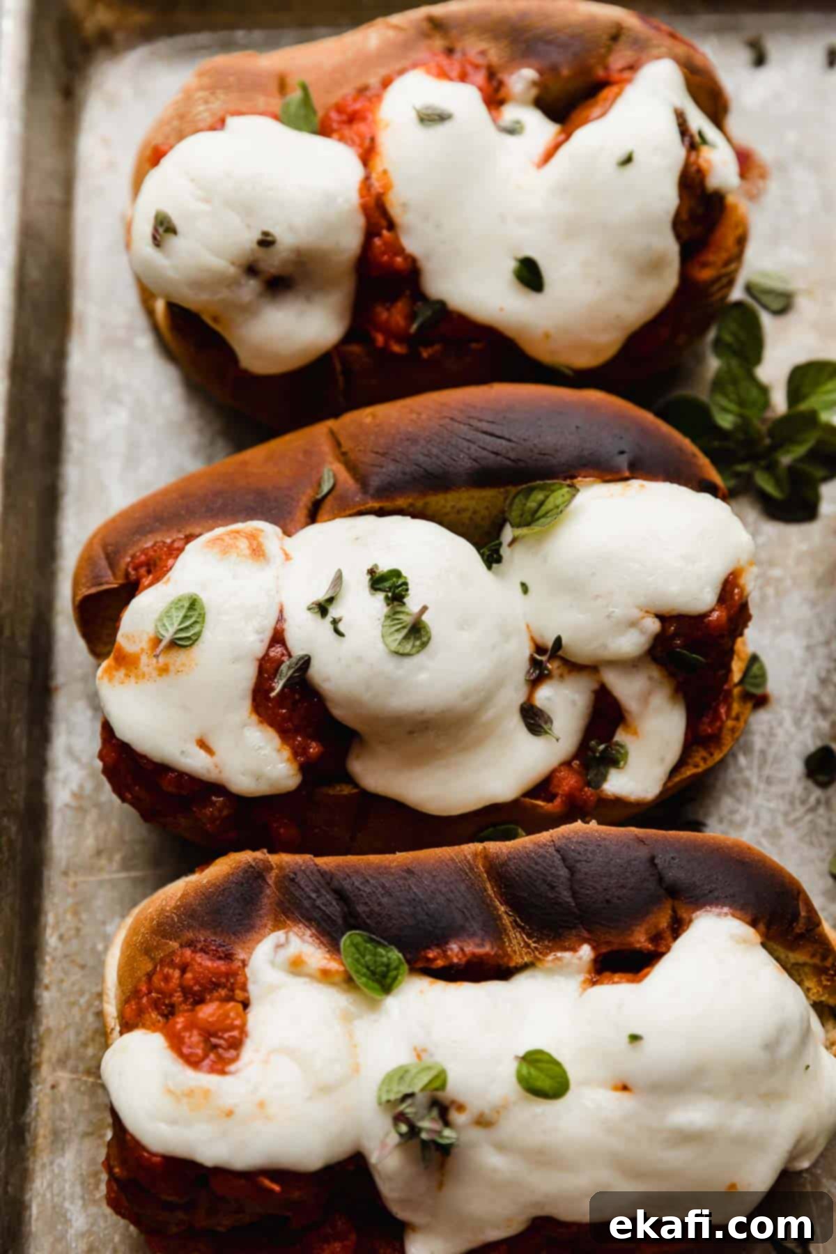 Classic Italian Meatball Subs 5 Melted mozzarella cheese overtop of Italian Meatball Subs on a baking sheet.
